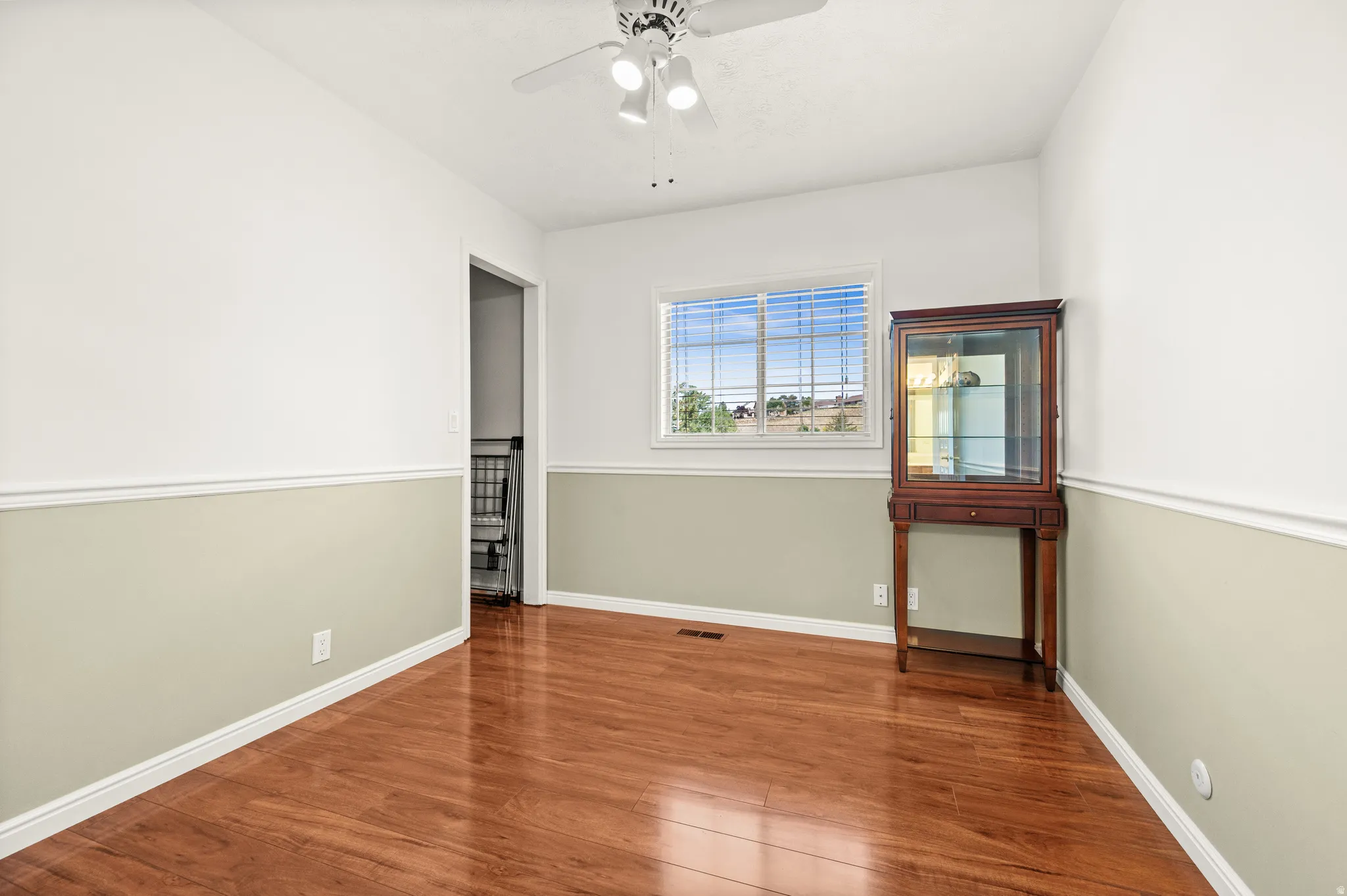 Interior room featuring wood-finish flooring, a white ceiling, and a ceiling fan with light fixture