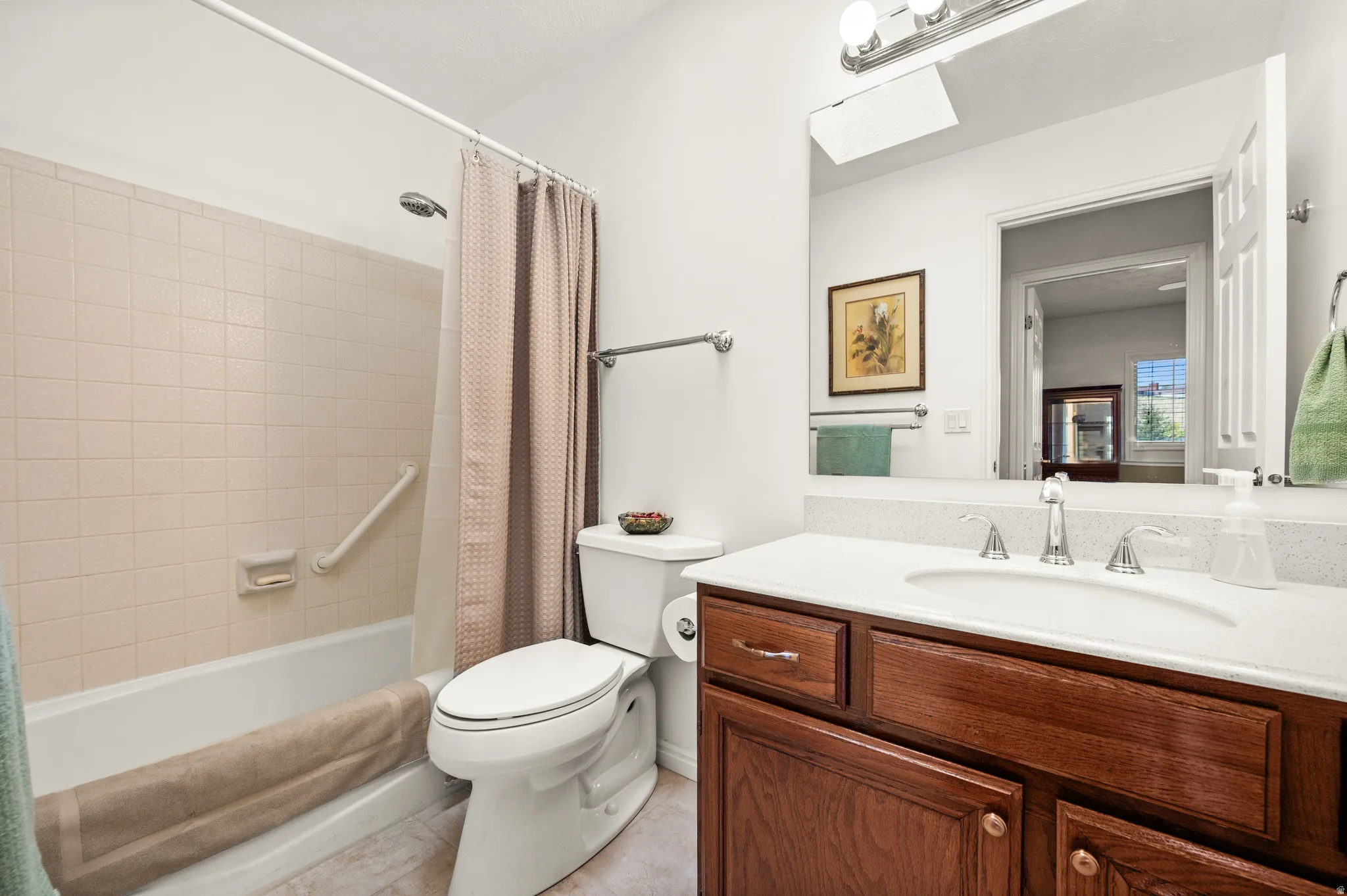 Bathroom featuring a wood-finish vanity with an integrated sink, a large mirror, and a tub with a tile surround