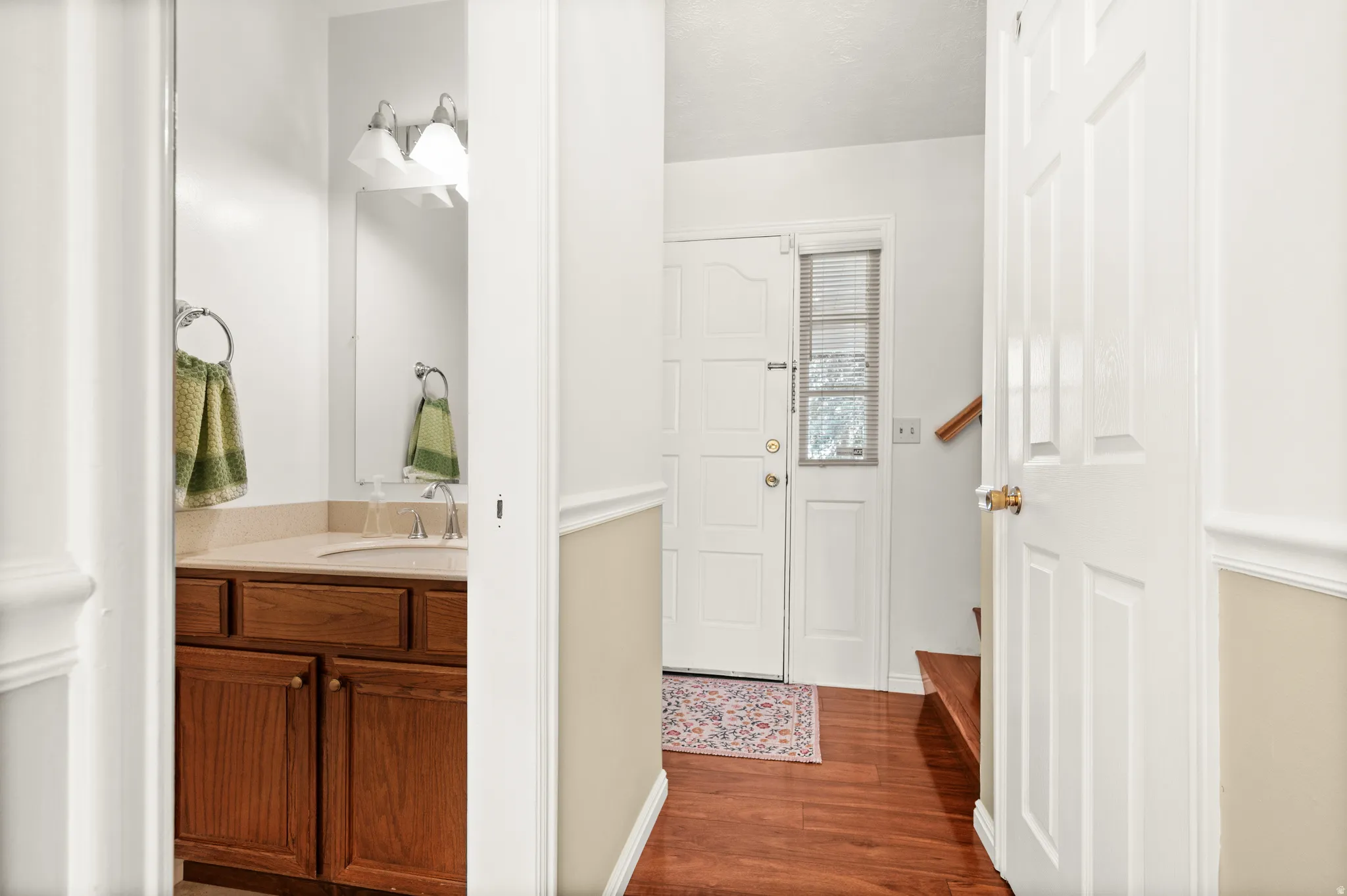 Foyer featuring wood-finish flooring, a paneled entry door with sidelight, and a staircase with a wood handrail