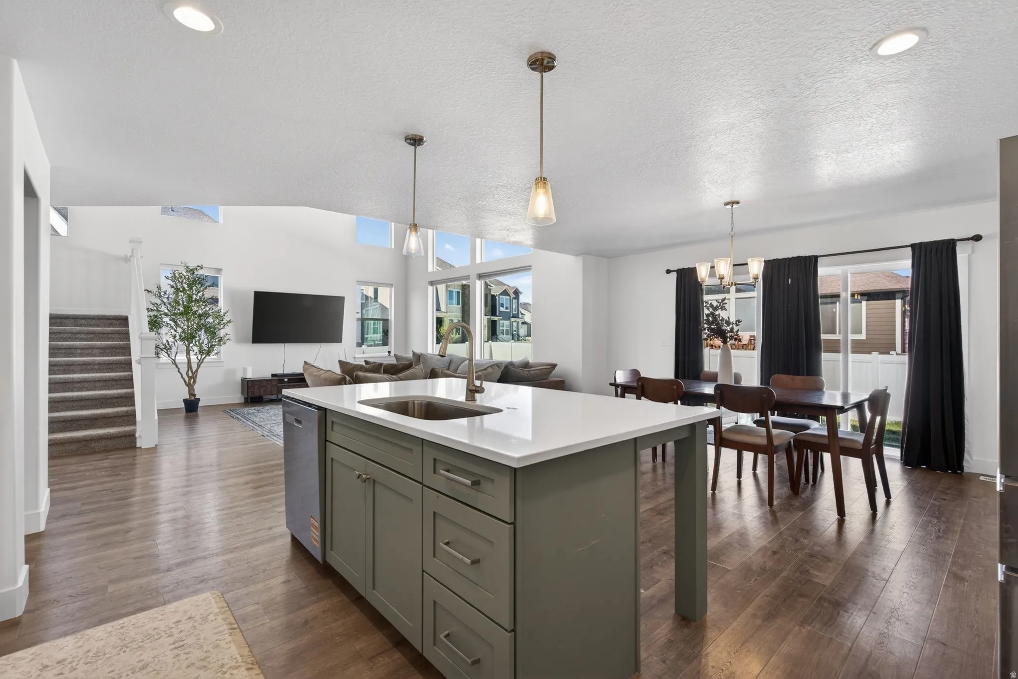 Open-concept living area featuring a kitchen island with a built-in sink, stainless steel dishwasher, and quartz countertop