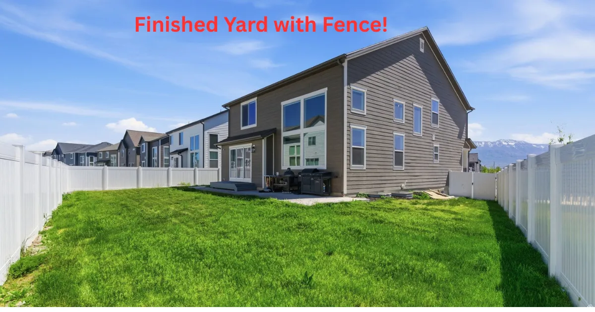 Expansive backyard featuring a green lawn and white vinyl fencing