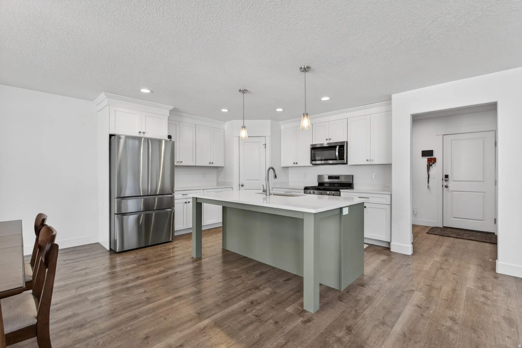 Kitchen featuring a central island with a contrasting base, white quartz countertops, and white shaker-style cabinetry