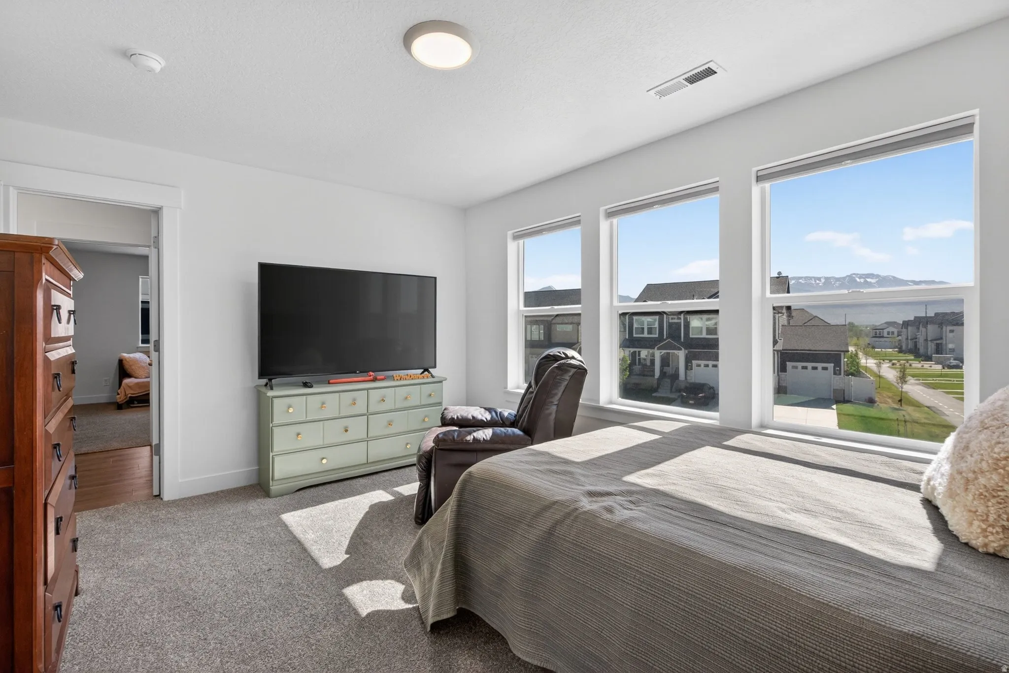 Room featuring three large windows showcasing mountain scenery