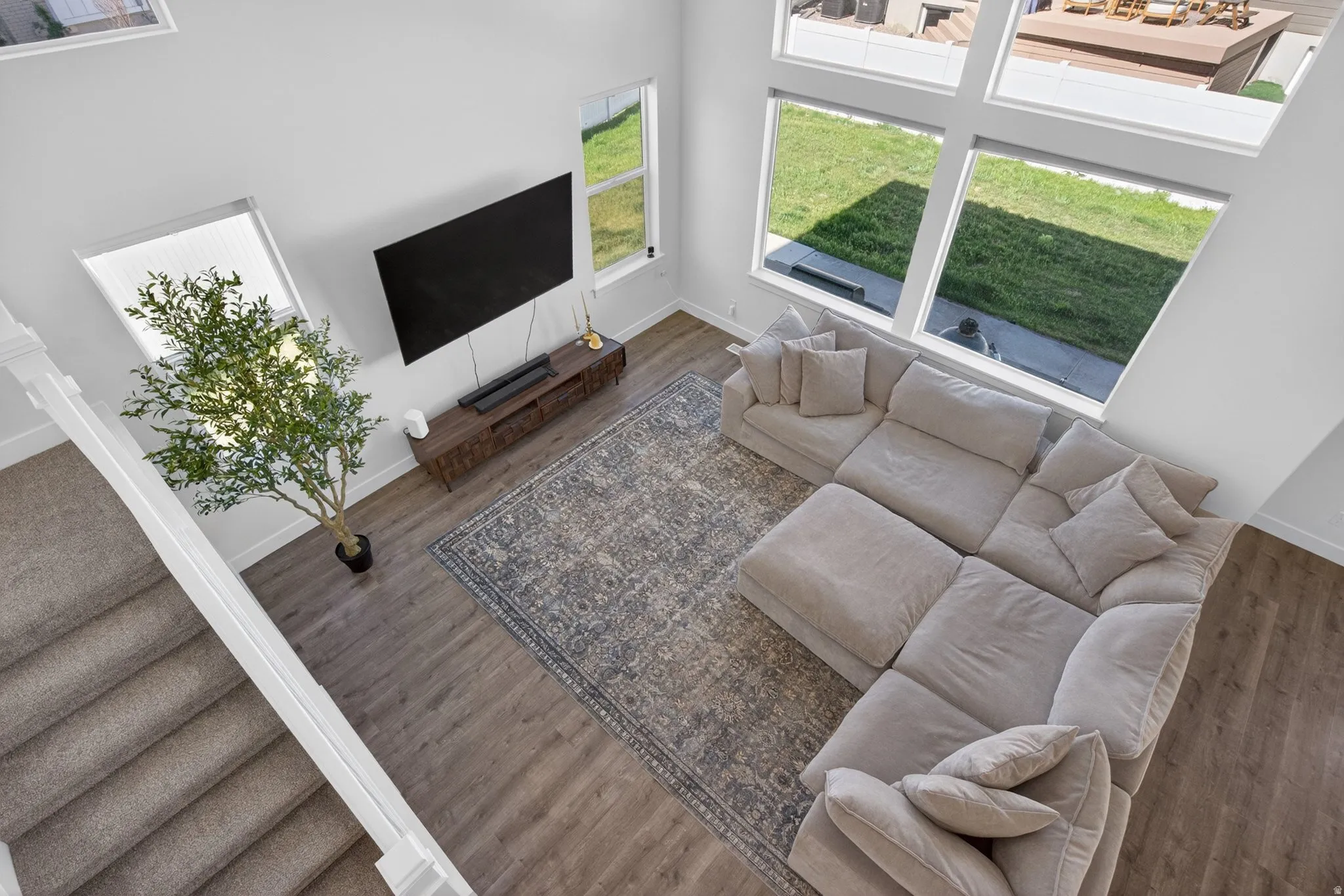 Living area featuring high ceilings, LVP flooring, a large area rug, and multiple windows providing natural illumination