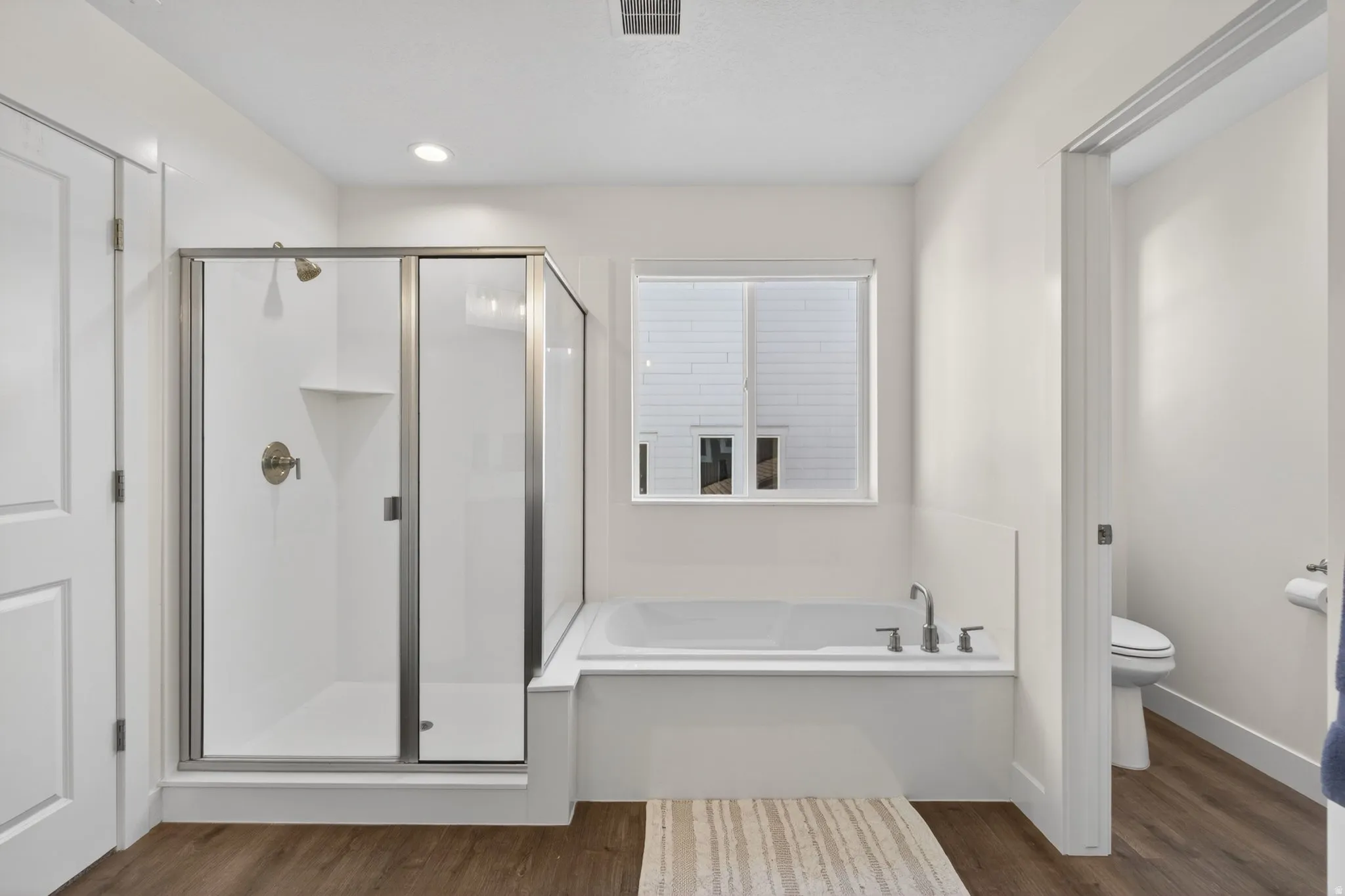 Bathroom featuring a glass-enclosed shower with, a built-in tub with chrome fixtures, and lvp flooring