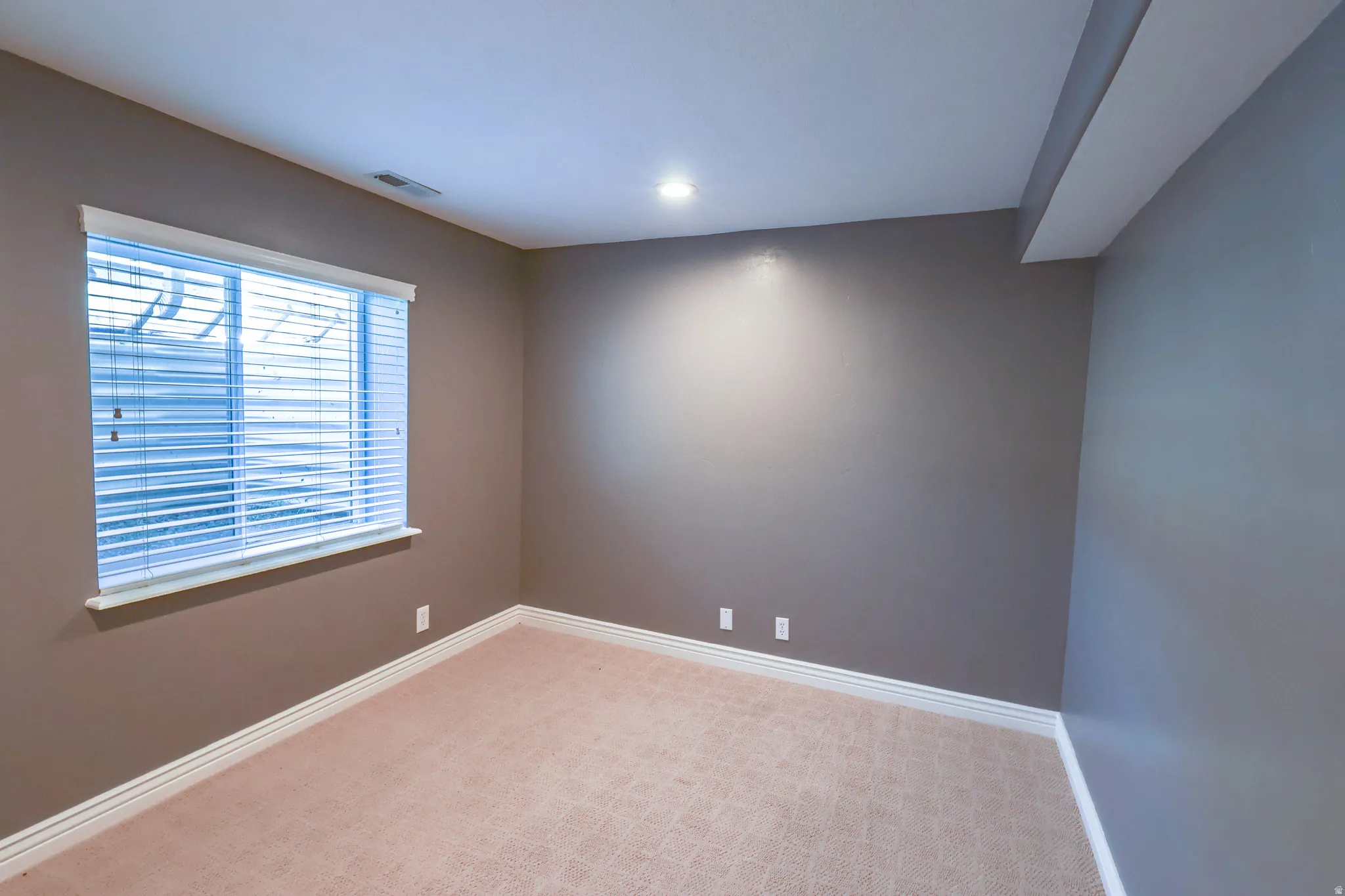 Room with neutral wall paint, recessed lighting, and light-toned patterned carpet