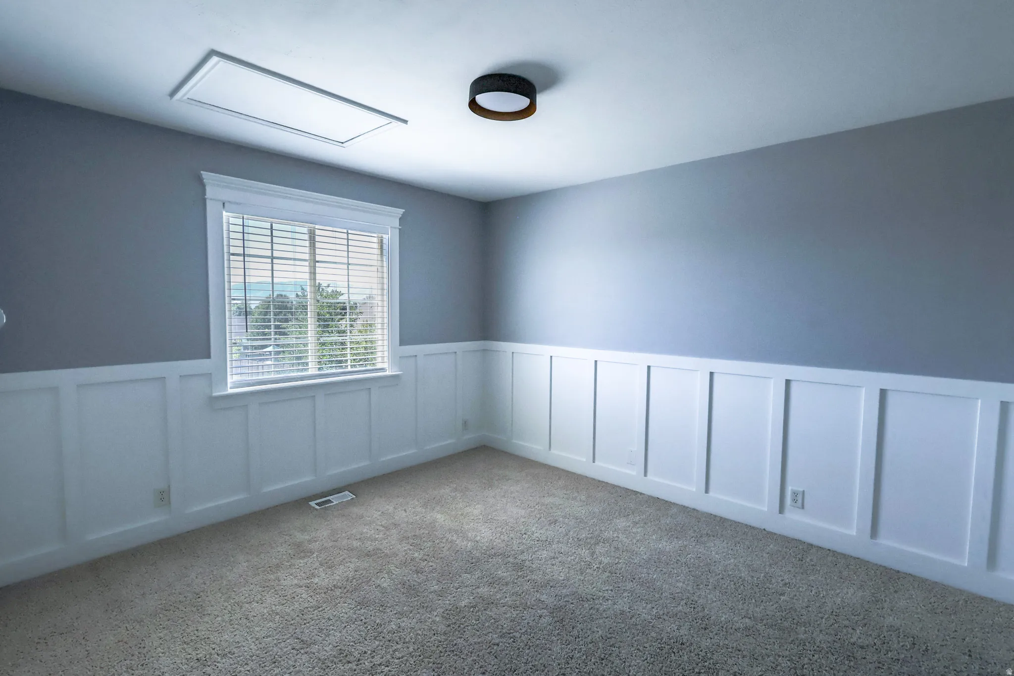 Interior room featuring two-tone walls with white board and batten wainscoting and light gray paint