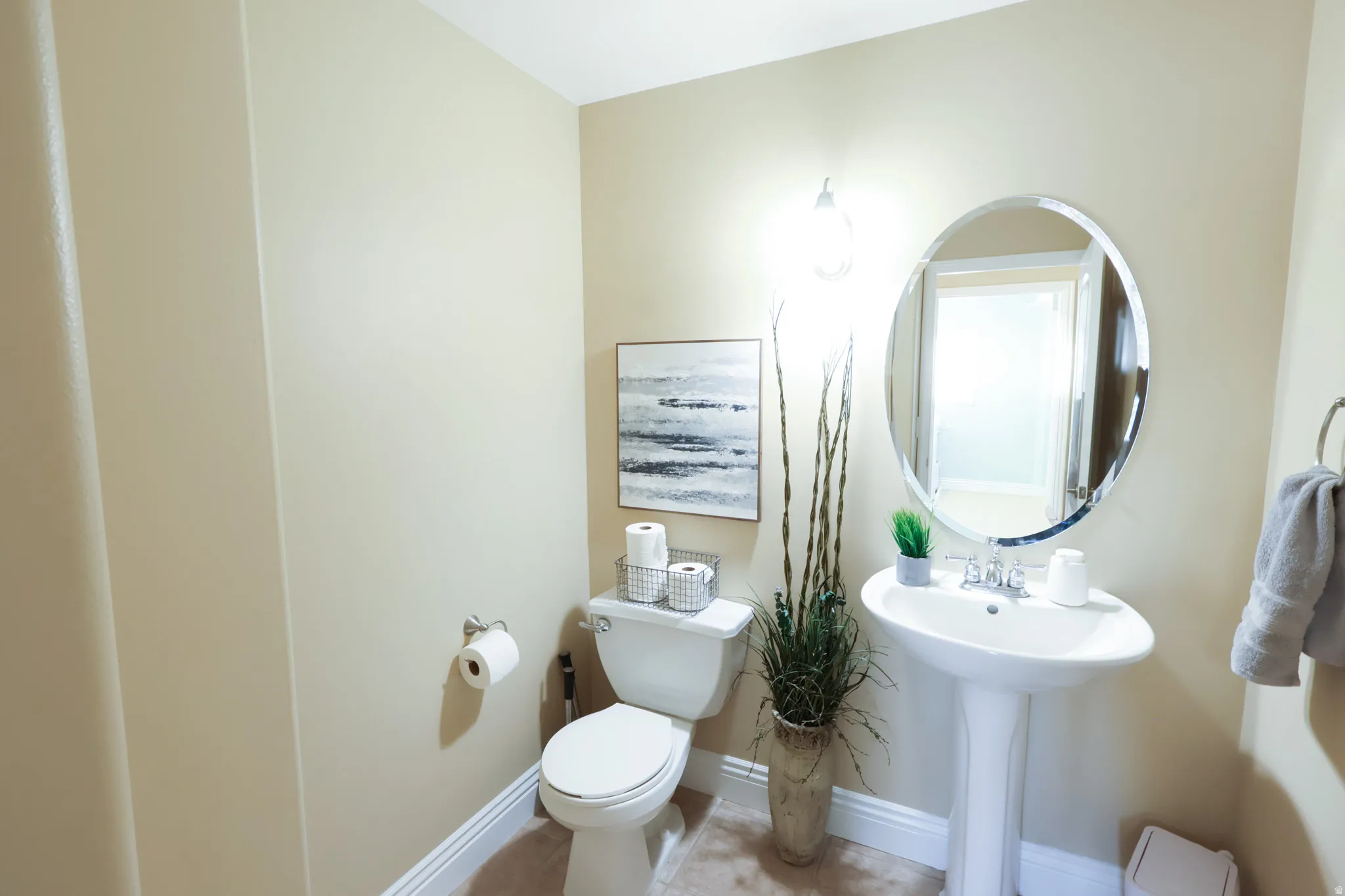 Pedestal sink with chrome fixtures and an oval framed mirror