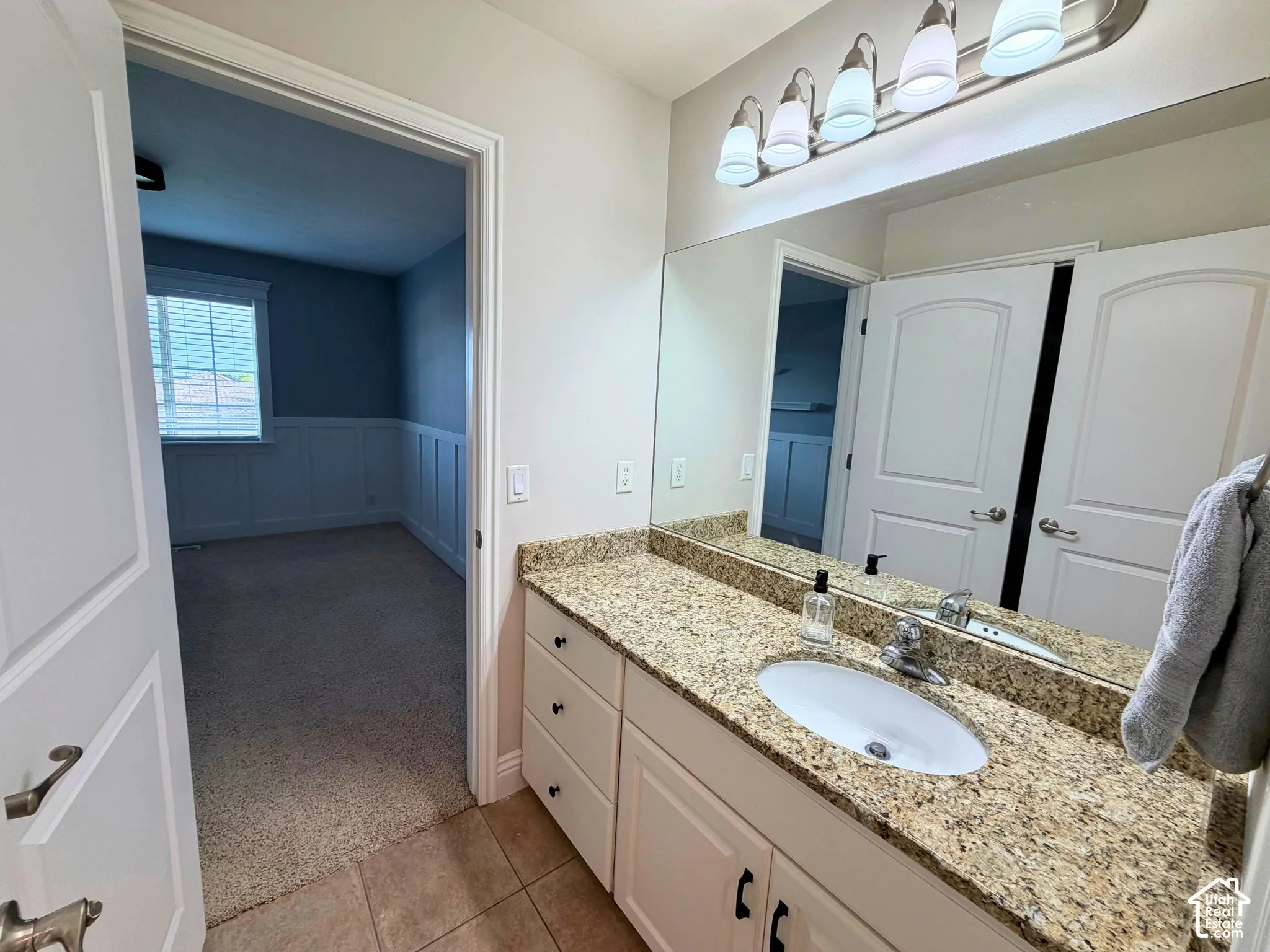 Vanity with an integrated sink, granite-look countertop, and a four-light fixture