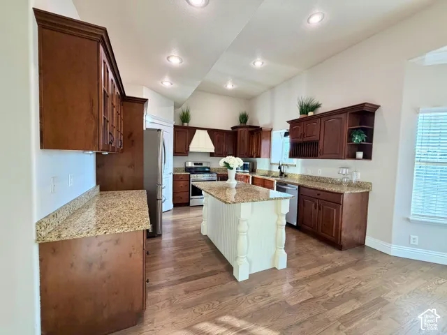 Kitchen featuring wood-finish flooring, recessed lighting, wood cabinetry, stone countertops, and a center island