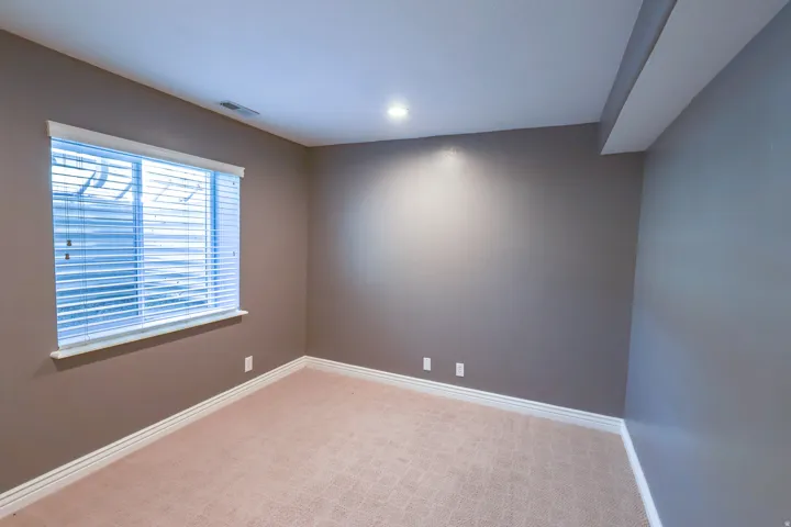Room with neutral wall paint, recessed lighting, and light-toned patterned carpet