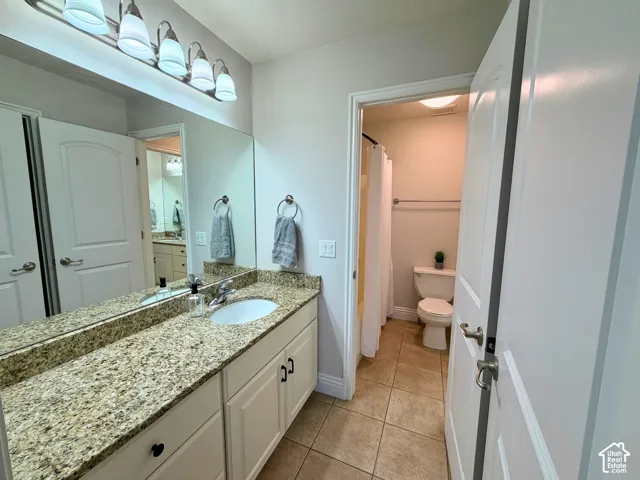 Bathroom featuring a vanity with a granite-style countertop, integrated sink, and white cabinetry