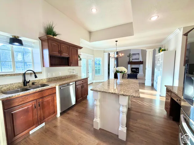 Kitchen featuring wood-finish flooring, granite countertops, stainless steel appliances, and a central island with a decorative base