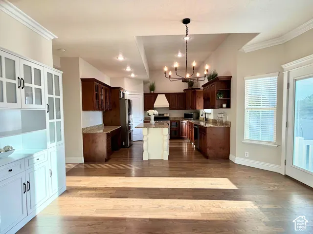 Open-concept kitchen with wood-finish flooring, dark wood cabinetry, granite countertops, and a central island