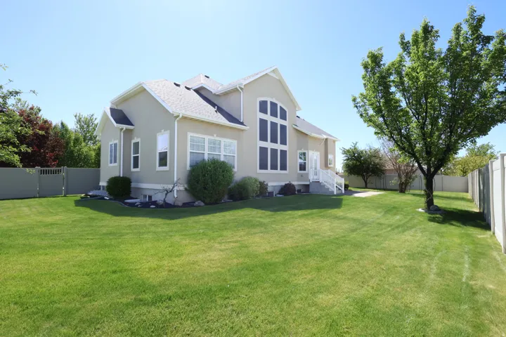 Expansive rear lawn with mature trees and a vinyl privacy fence