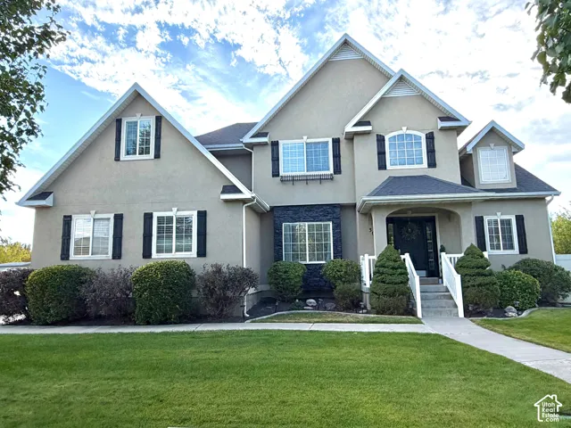 Stucco exterior with stone accents, multiple gables, covered entry, and a paved walkway
