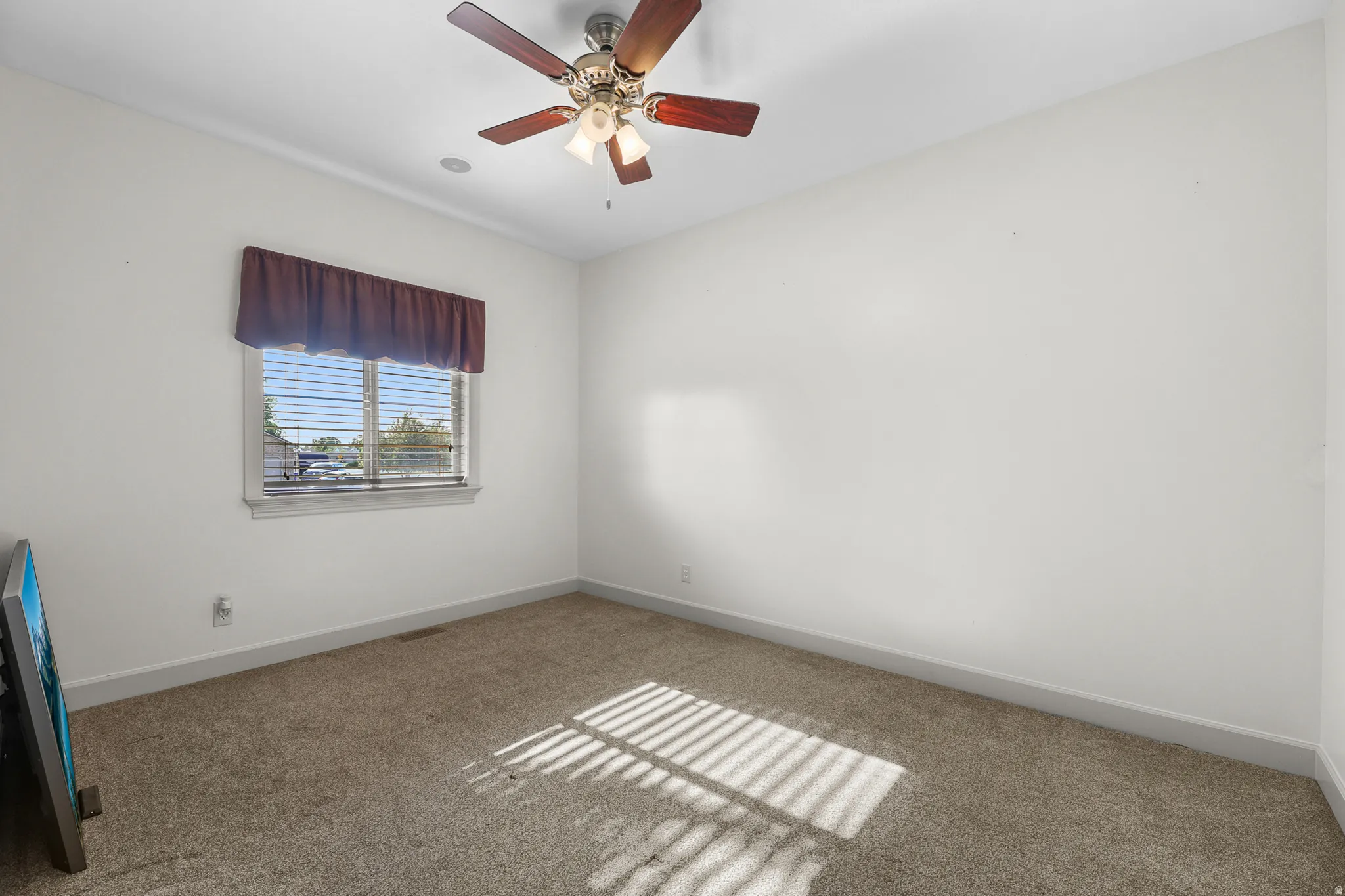 Room featuring a ceiling fan with integrated lighting, a window with blinds and a valance, light-toned carpeting, and white baseboards