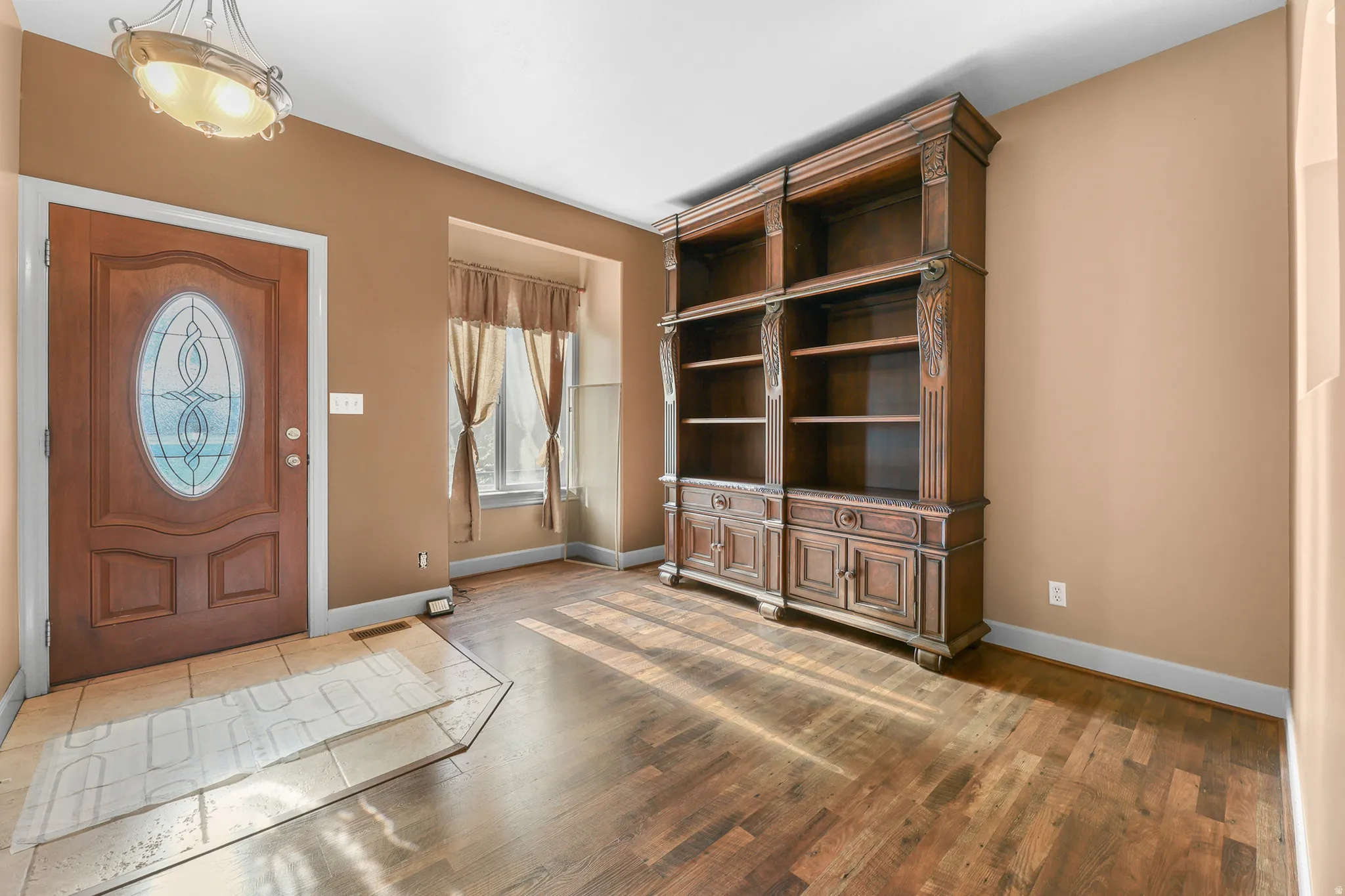 Entryway featuring a wood-finish door with decorative glass, tiled flooring, a recessed window, and wood-finish flooring