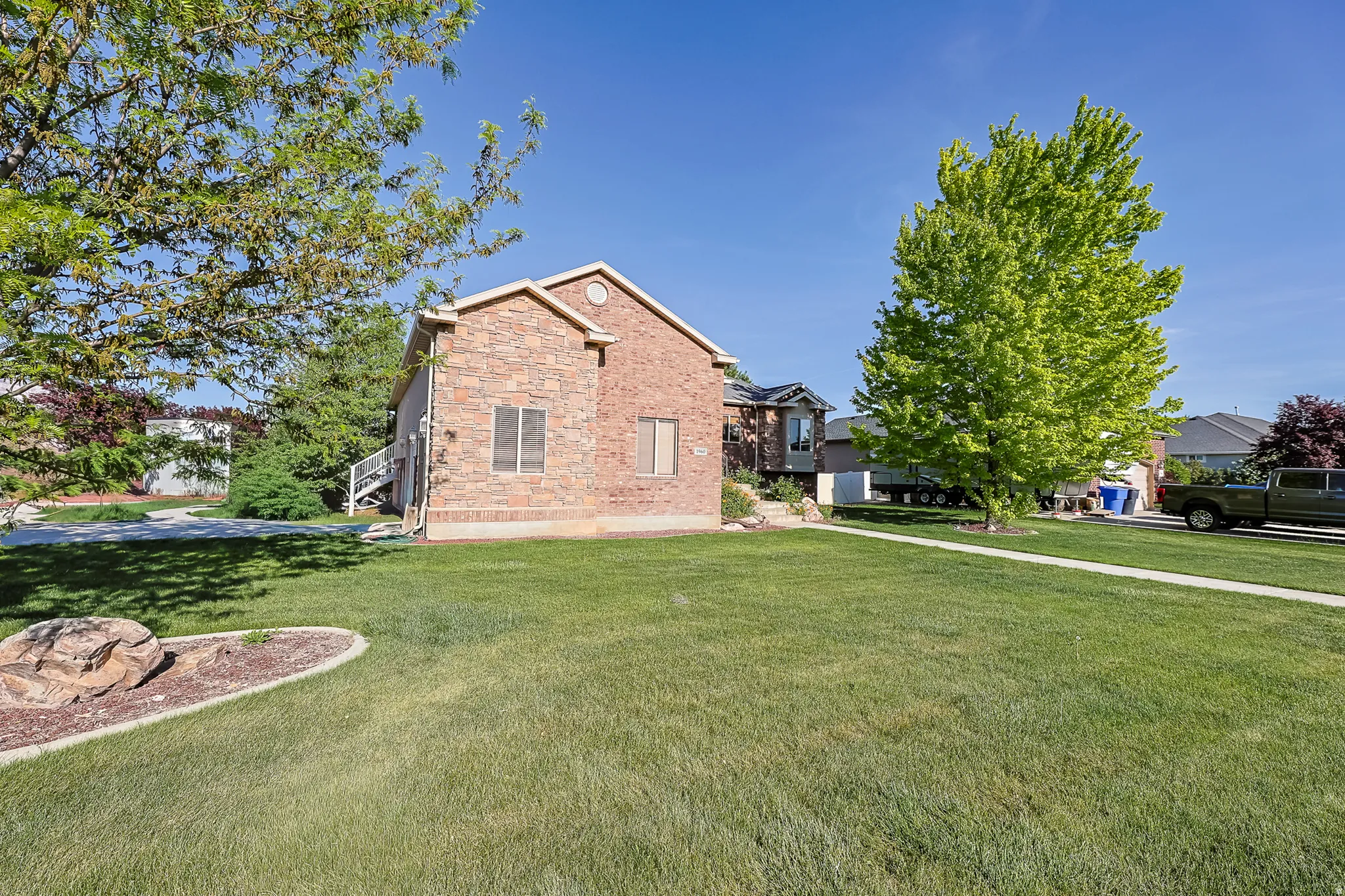 Brick and stone facade residence featuring a front lawn and paved pathway