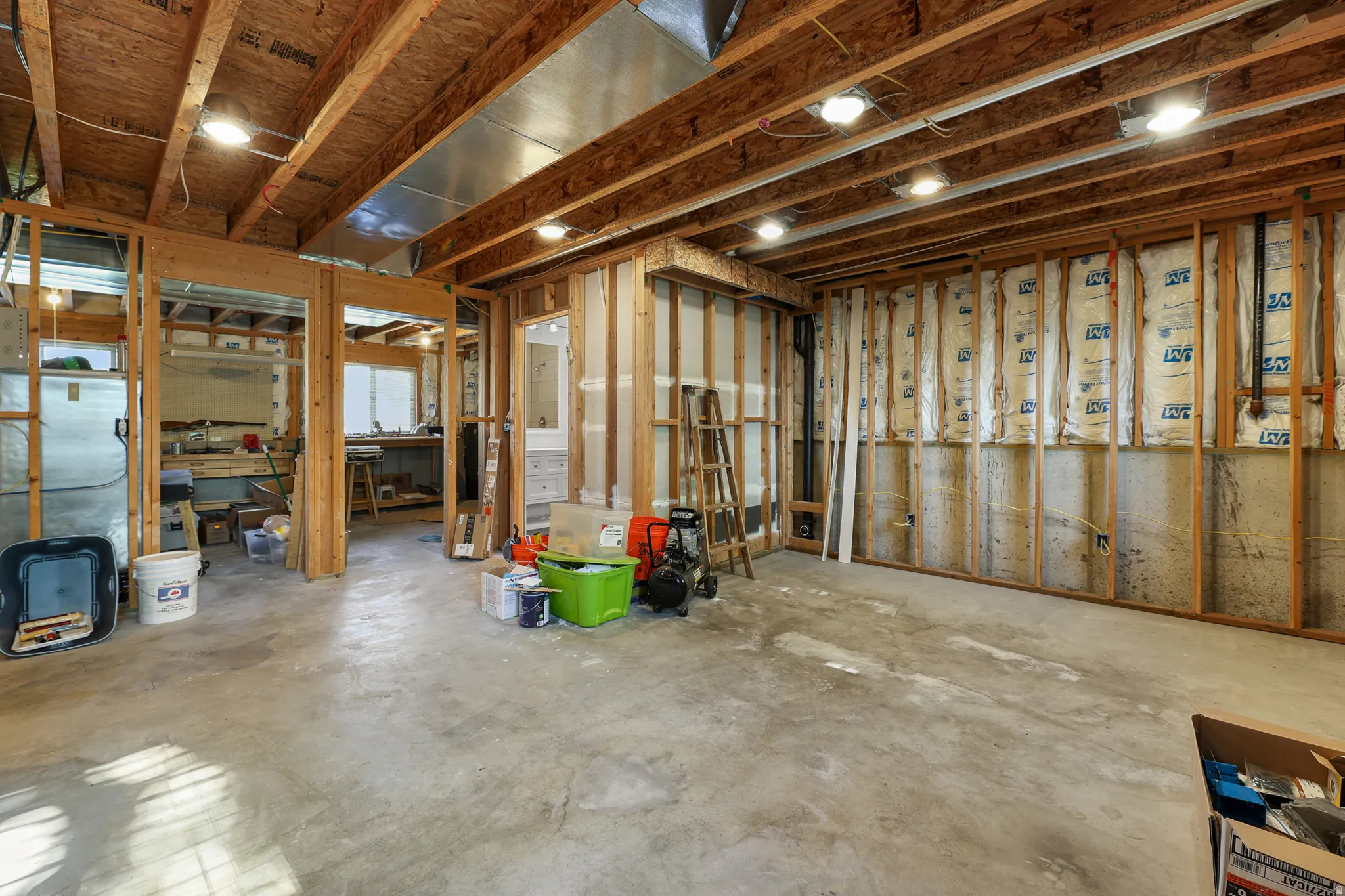 Unfinished lower level with concrete flooring, exposed wood joists, recessed lighting, and framed wall structures