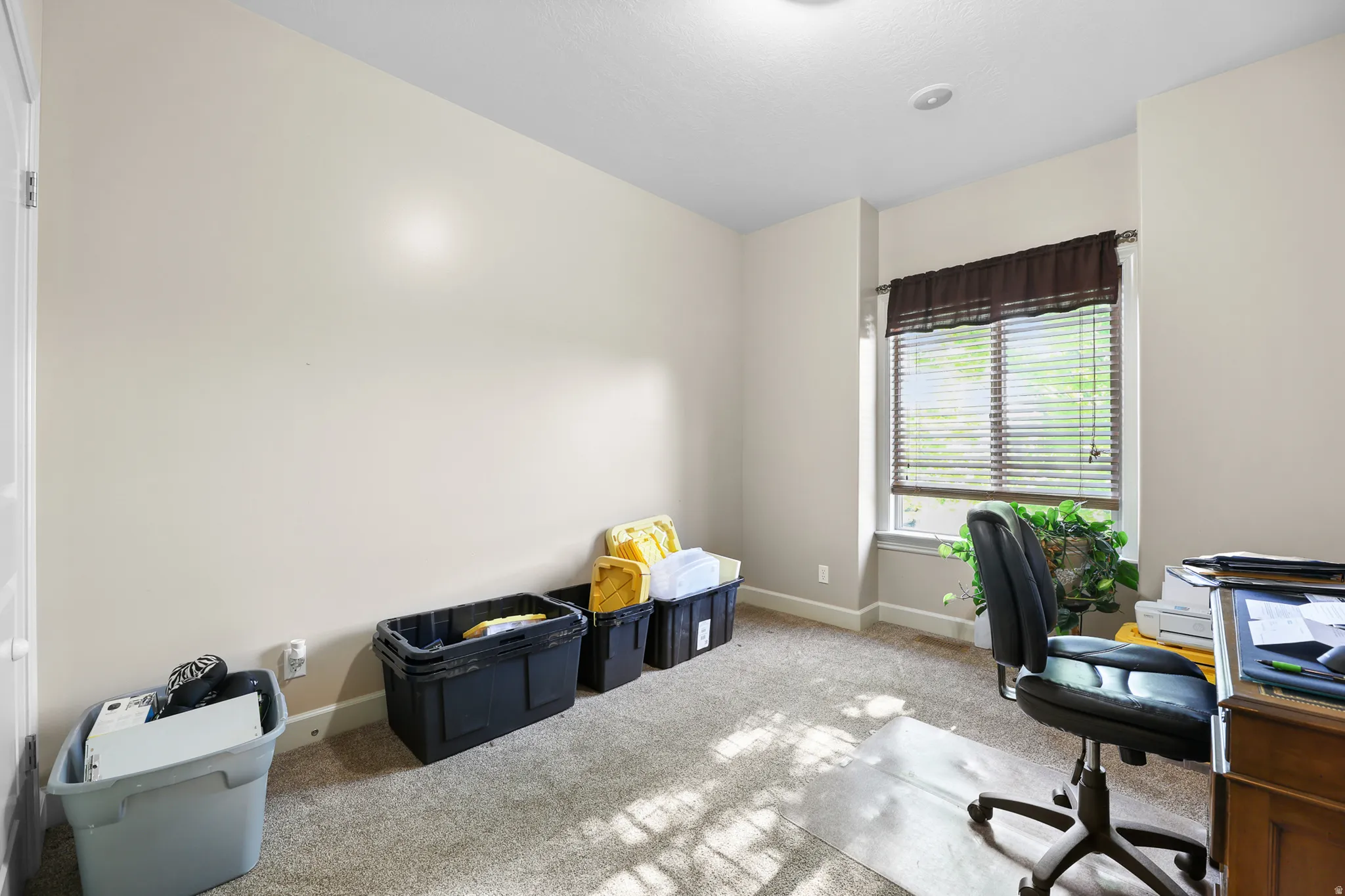 Carpeted room with a window featuring horizontal blinds and a fabric valance
