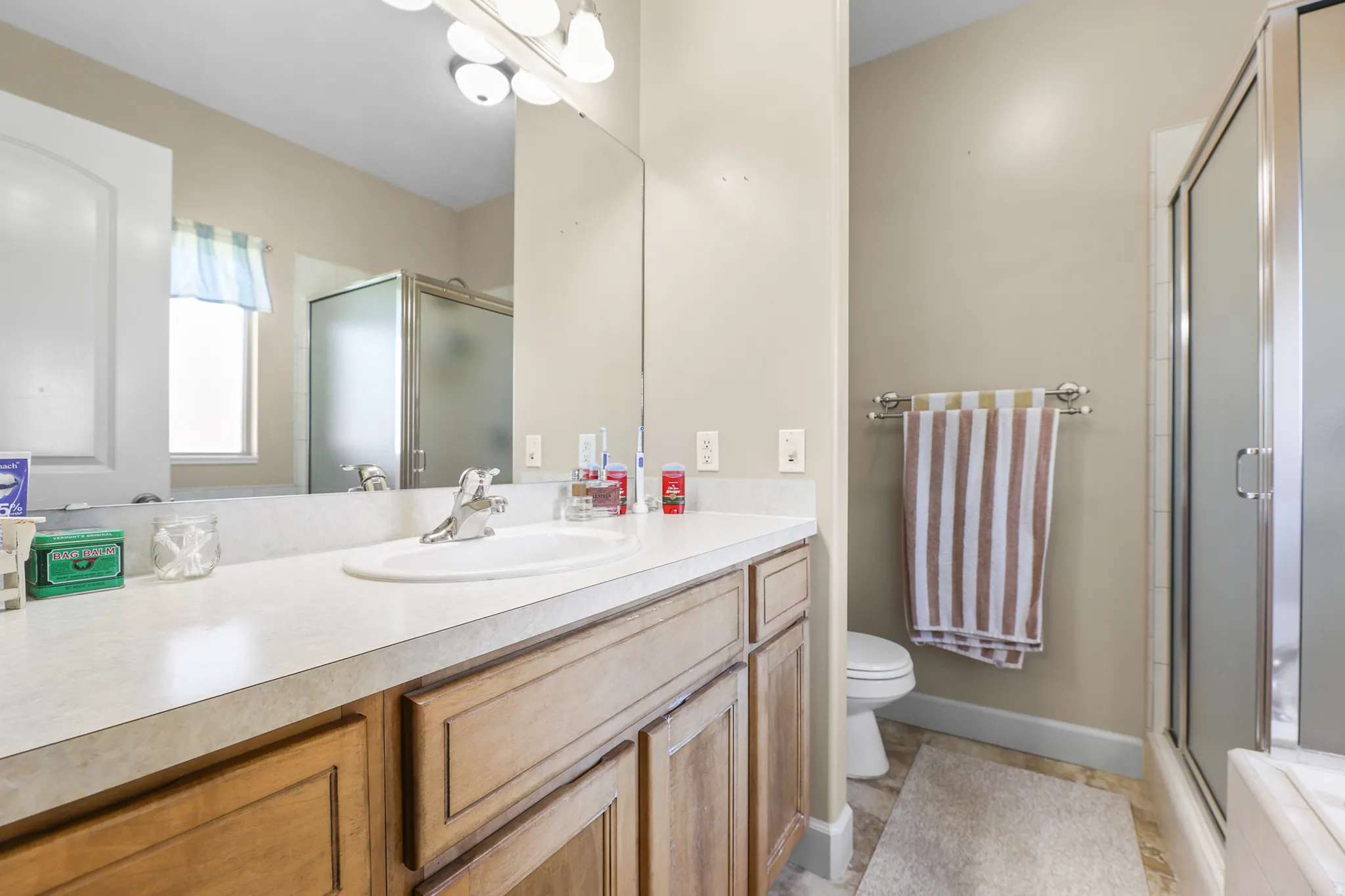 Bathroom featuring a vanity with an integrated sink, a light-toned countertop, and wood-finish cabinetry