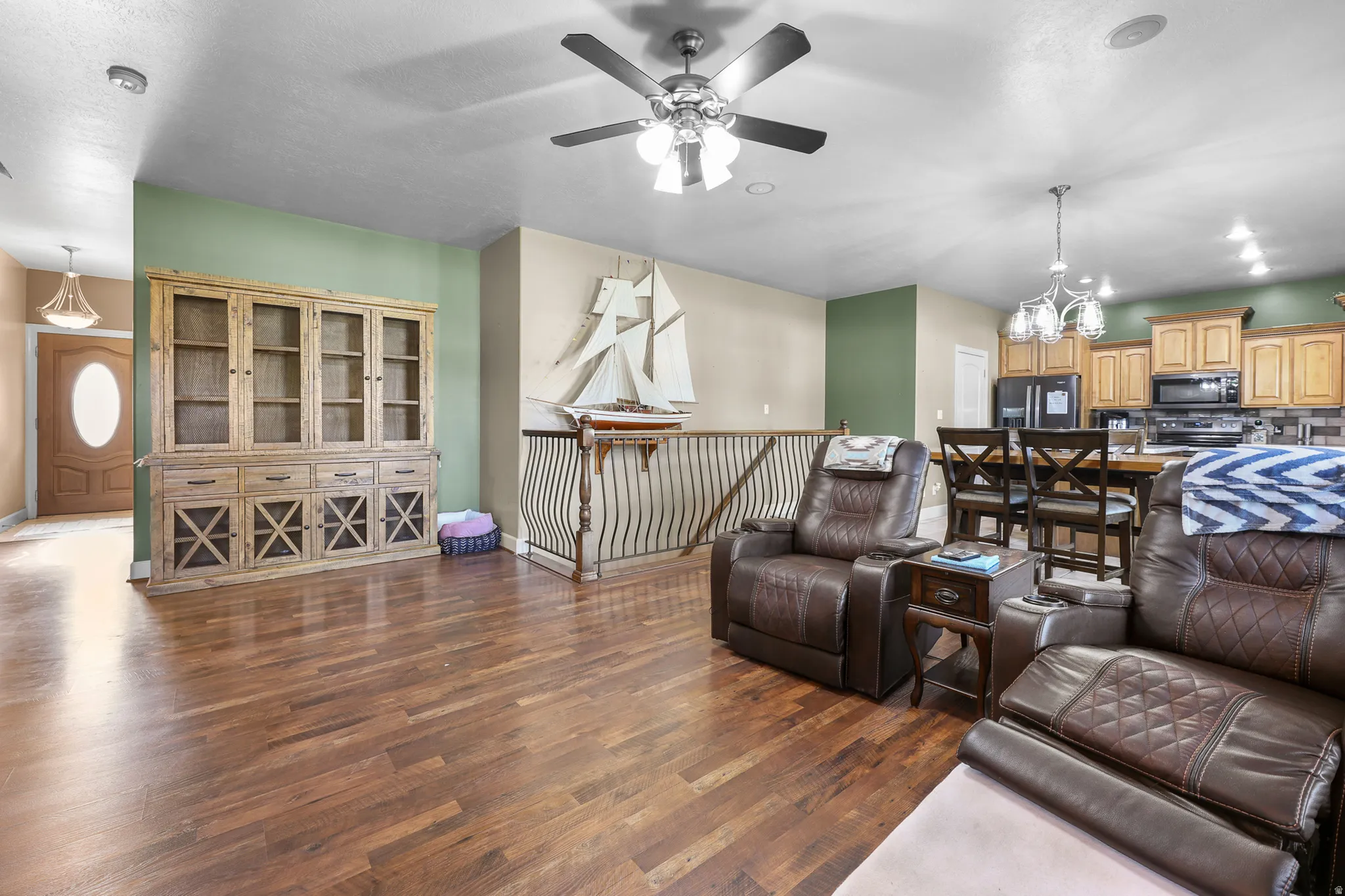 Open concept living area featuring wood-finish flooring, a ceiling fan, and a built-in display cabinet