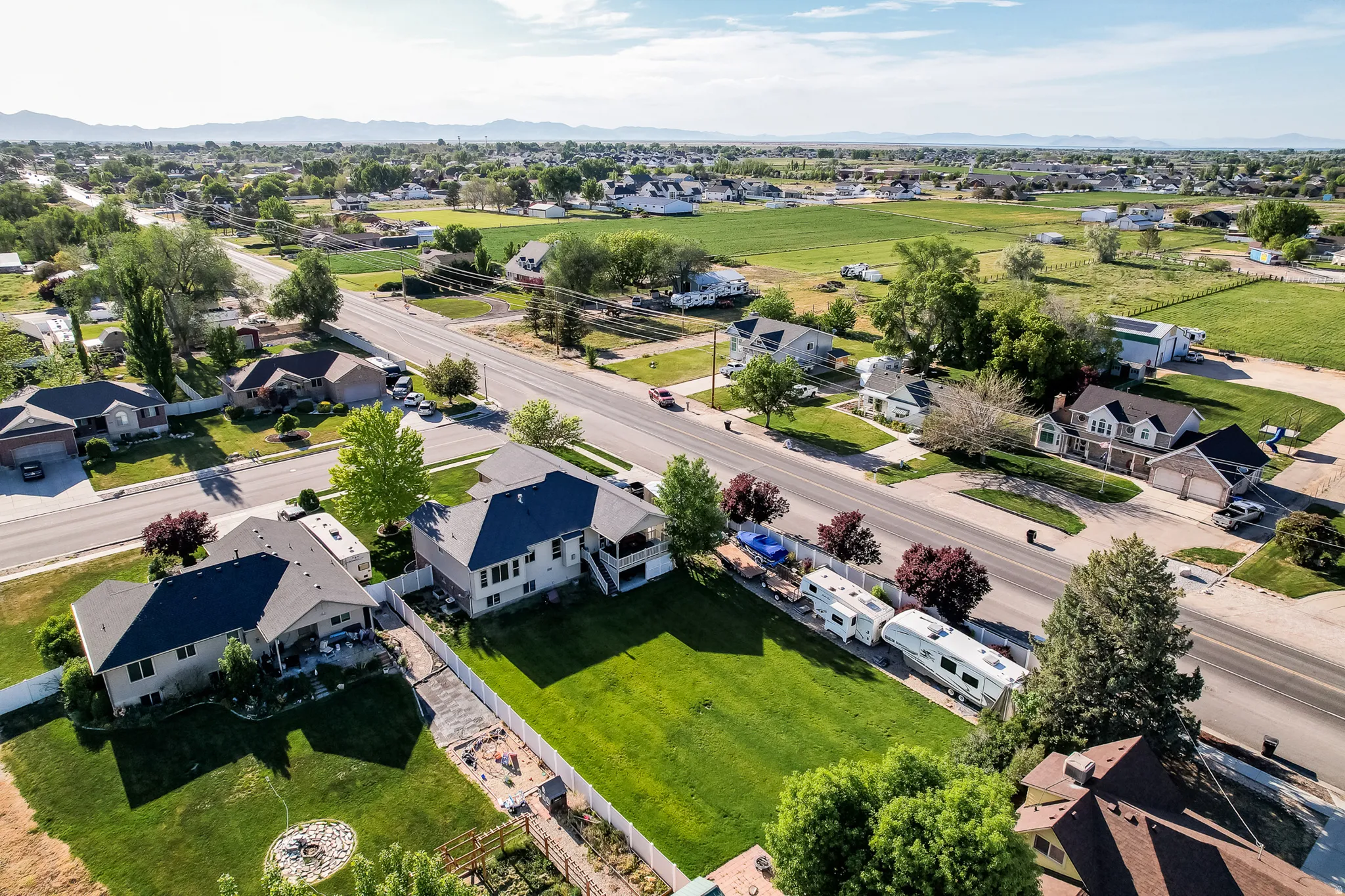 Expansive lot featuring a large grassy area, established trees, and a concrete driveway