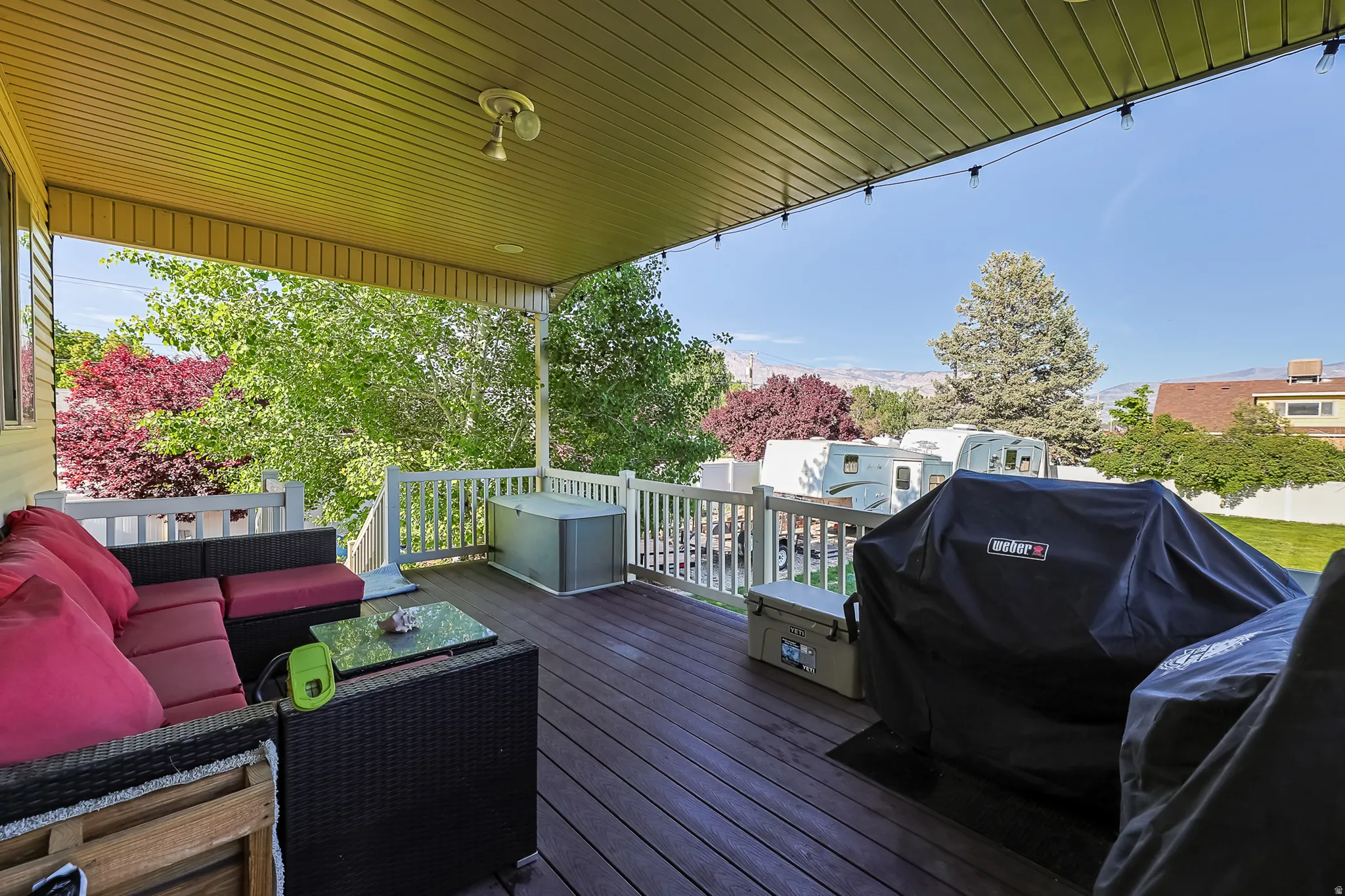 Covered outdoor deck featuring composite decking, white railing, and a tongue-and-groove ceiling