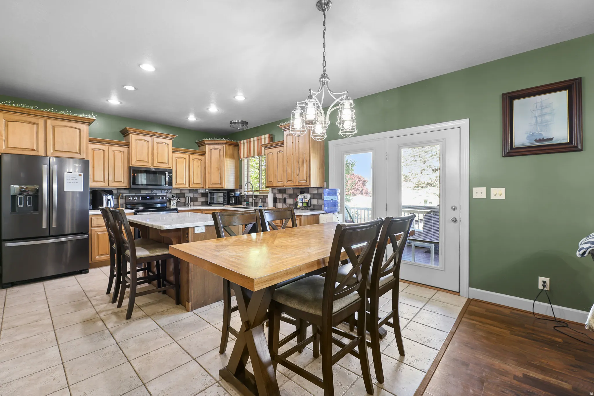 Spacious kitchen featuring light wood cabinetry, a central island with countertop seating, and a large dining table