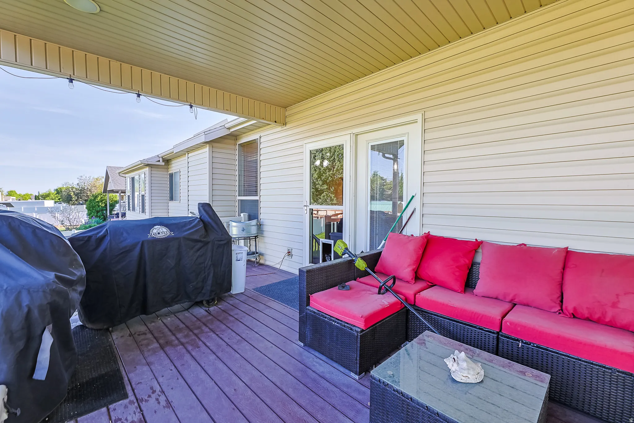 Covered patio featuring a wood-finish deck, white vinyl siding, and recessed lighting