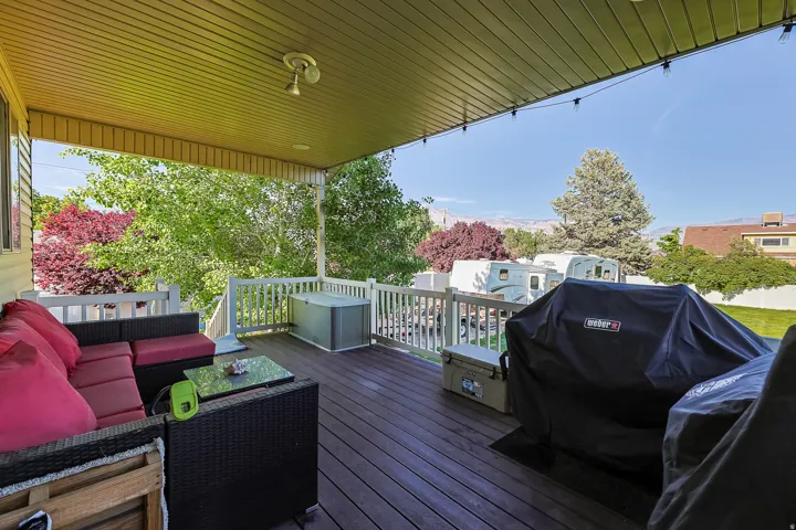 Covered outdoor deck featuring composite decking, white railing, and a tongue-and-groove ceiling