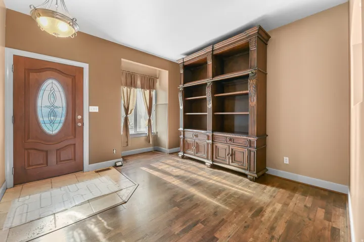 Entryway featuring a wood-finish door with decorative glass, tiled flooring, a recessed window, and wood-finish flooring