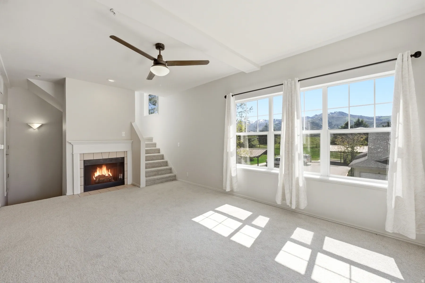 Carpeted living area featuring a fireplace with tile surround, white mantel, and hearth