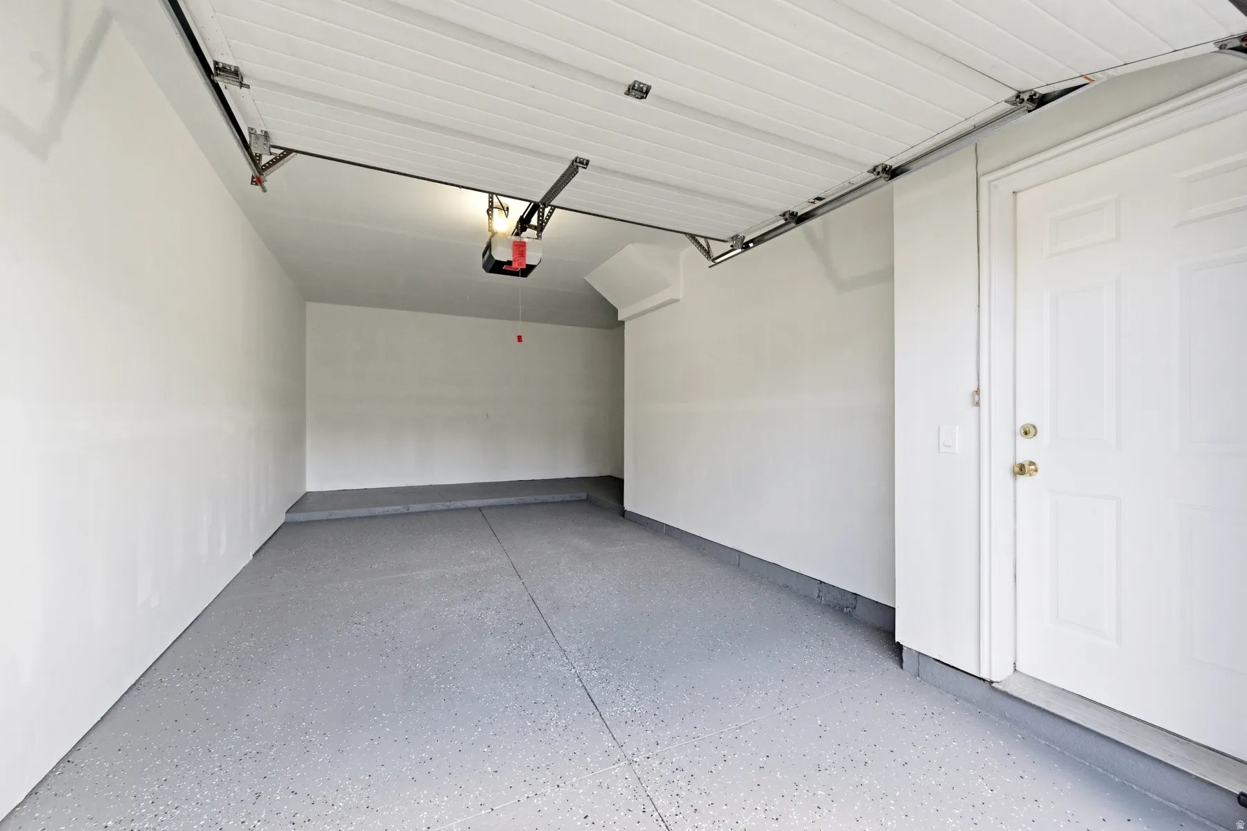Spacious garage featuring a durable epoxy-coated floor, painted walls, and an automatic garage door opener
