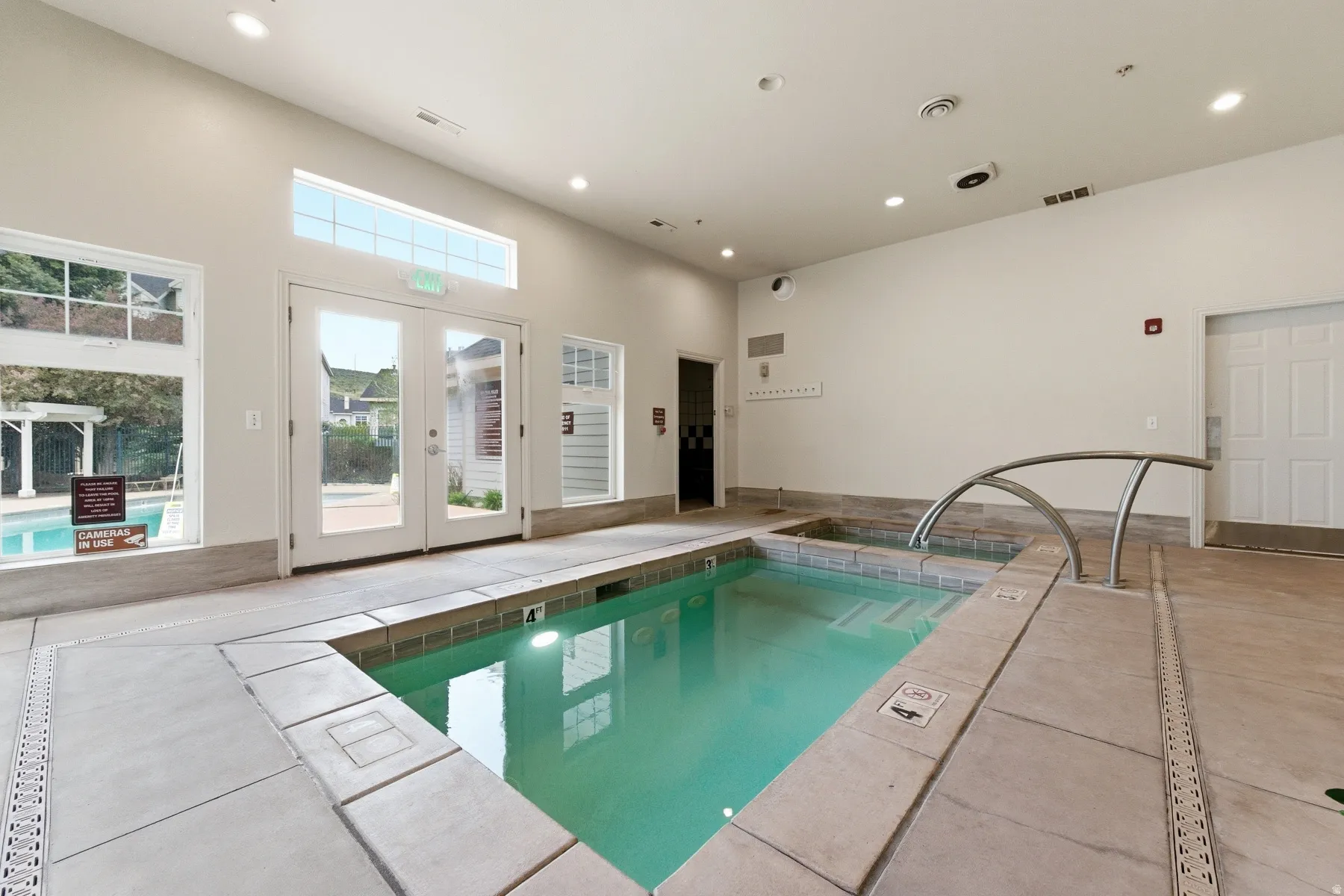 Indoor aquatic area featuring a large spa with an arched handrail and a smaller soaking tub