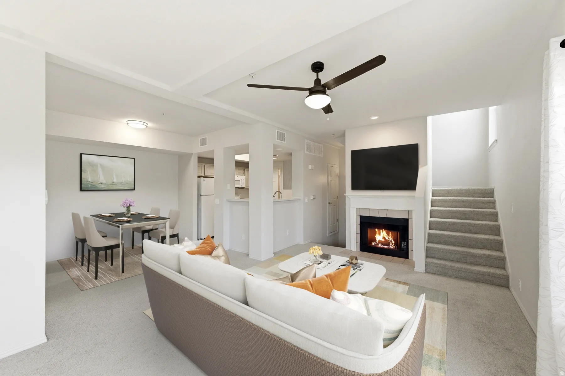 Spacious living area featuring carpet flooring, a ceiling fan, and a fireplace with a white mantel