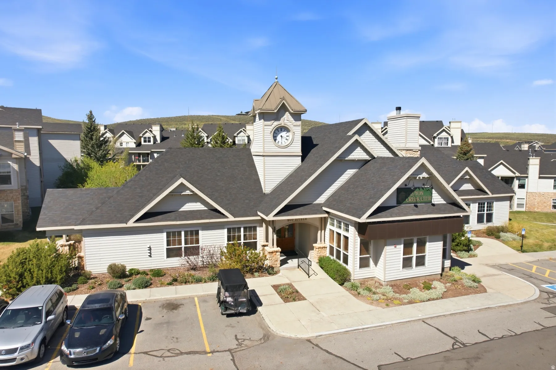 Central building featuring horizontal siding, a prominent clock tower, and dark shingle roofing