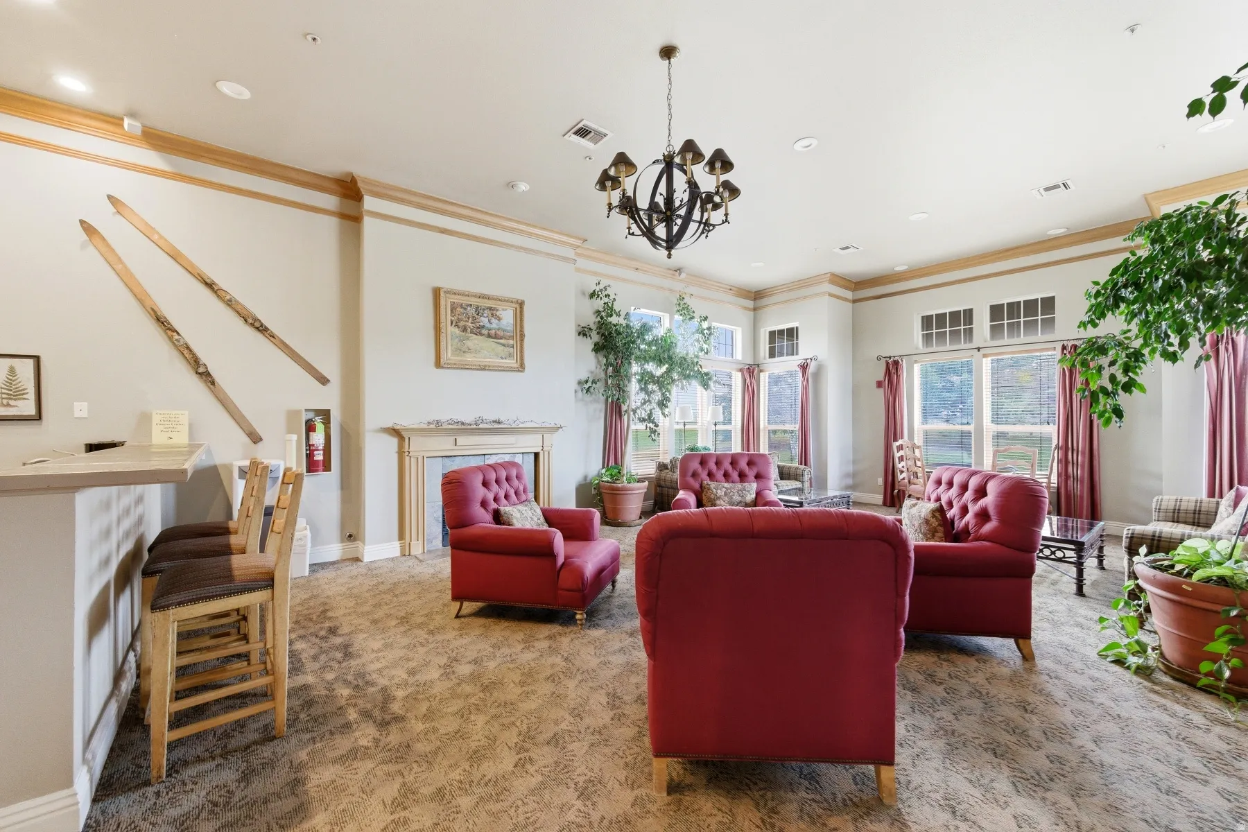 Spacious common area featuring patterned carpet flooring, a decorative chandelier, and extensive fenestration with transom windows