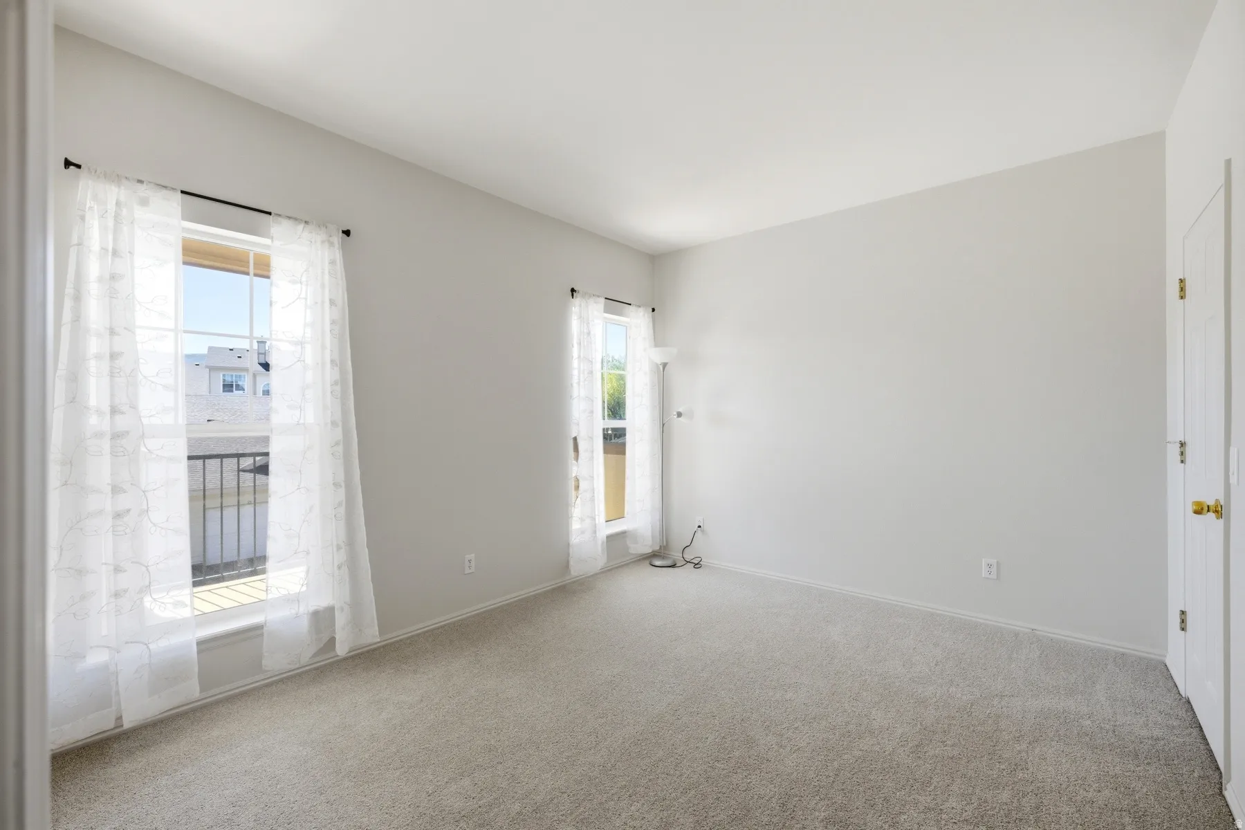 Bright room with two large windows, light gray walls, and light-colored carpeting