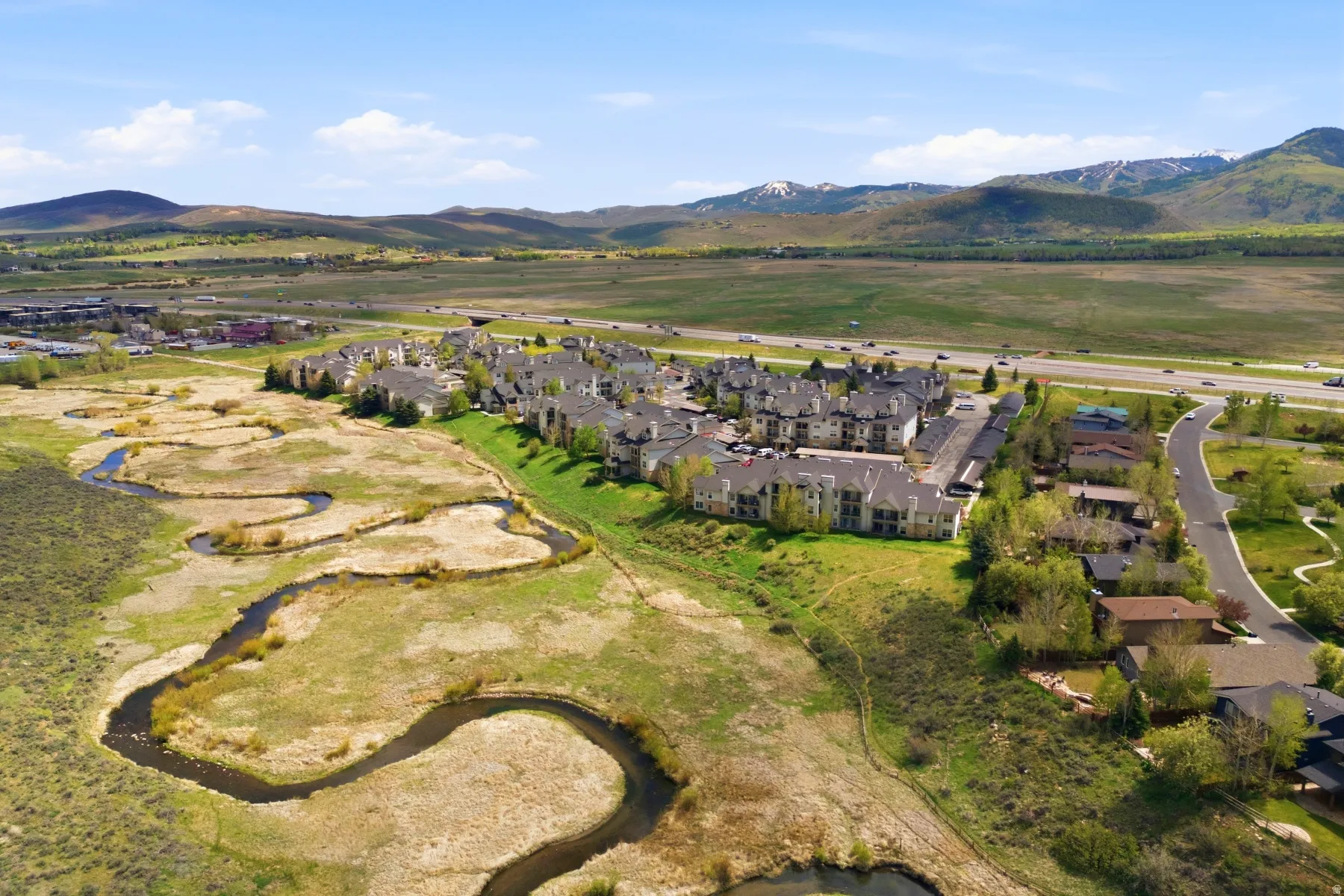Expansive aerial view showcasing properties bordered by a winding natural waterway and open fields