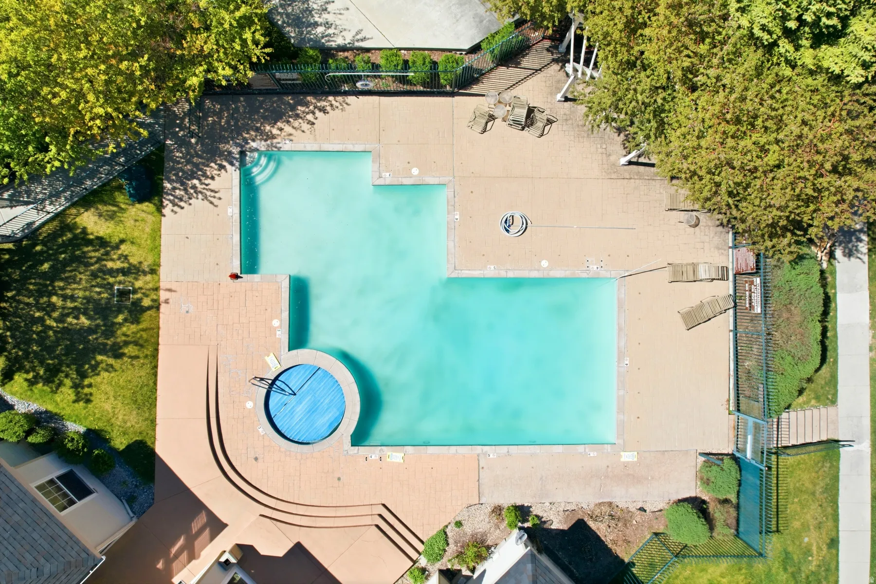 Expansive outdoor pool area featuring a large, irregular-shaped swimming pool and a circular spa with a cover