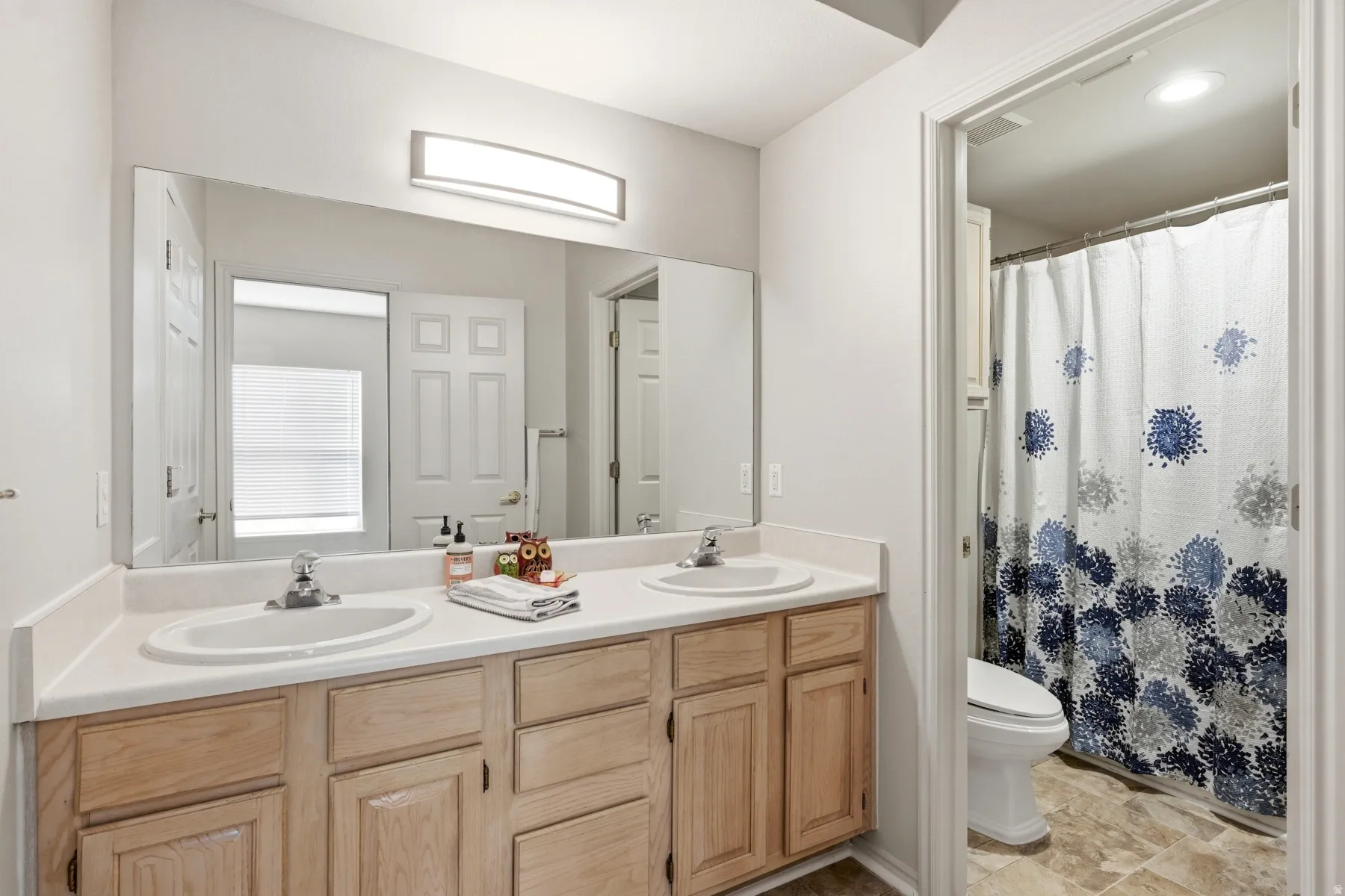 Double vanity with light wood-finish cabinetry and white countertops