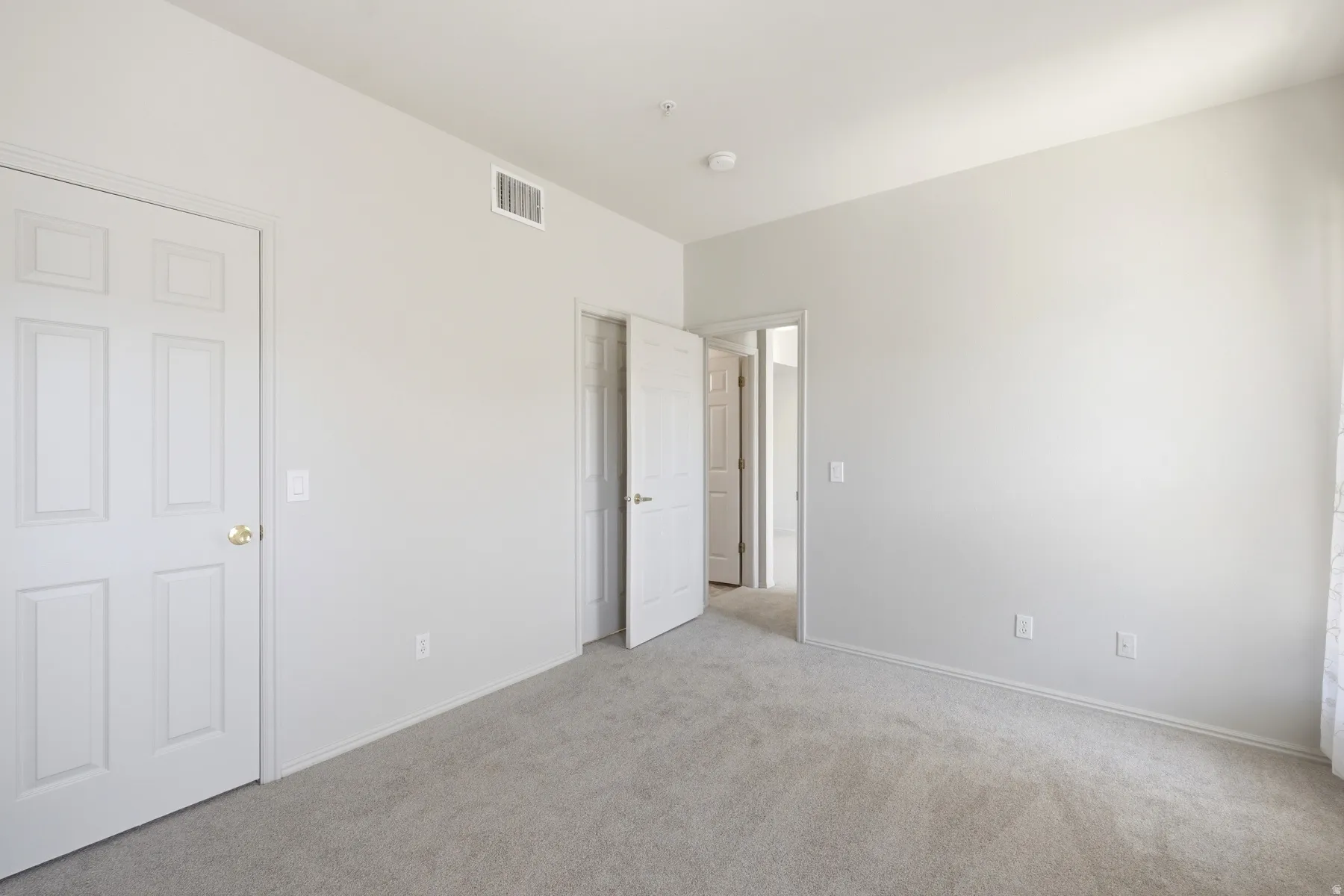 Neutral-toned room featuring light gray carpeting and white painted walls