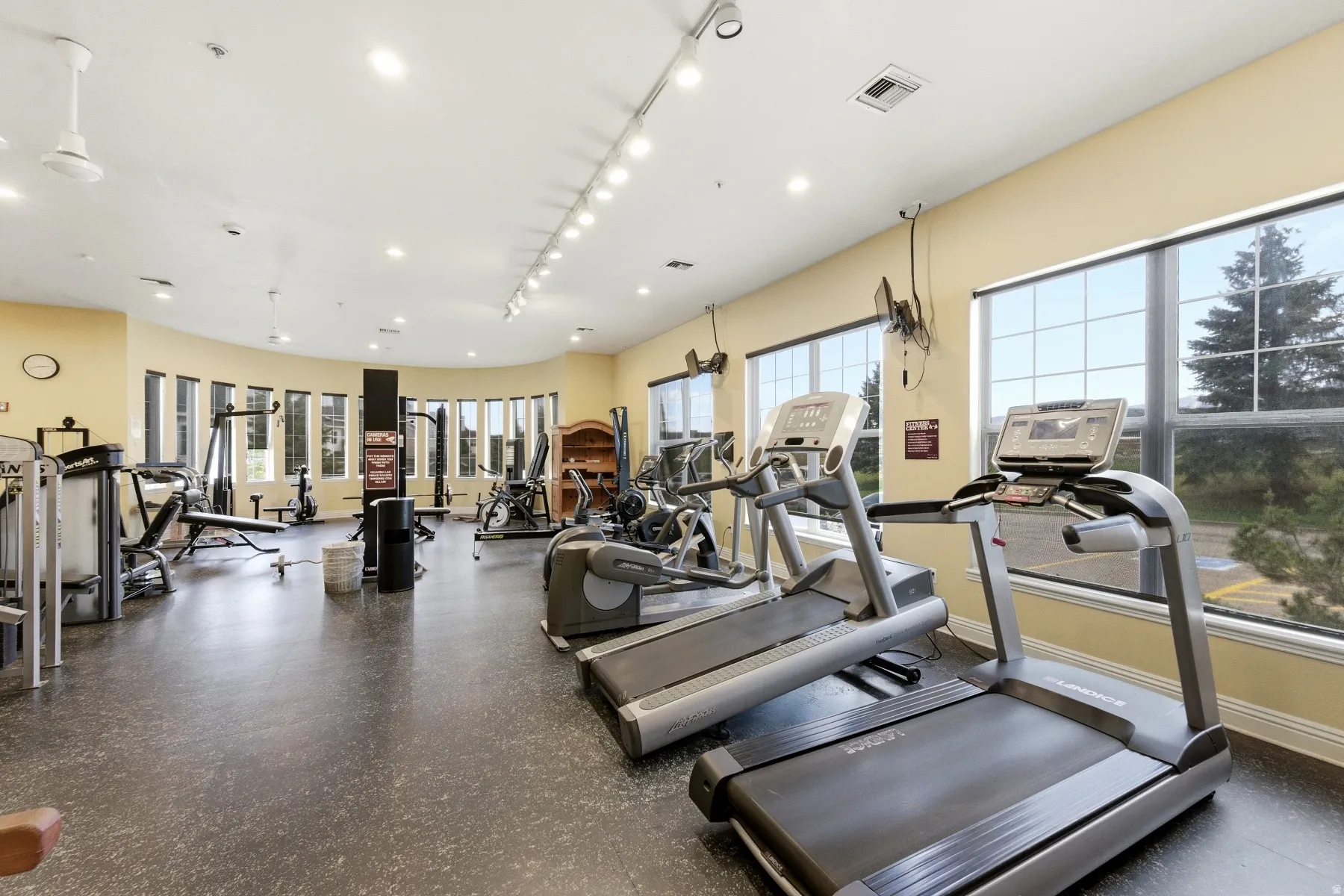 Fitness center featuring multiple treadmills, exercise equipment, expansive windows, recessed lighting, and resilient rubber flooring