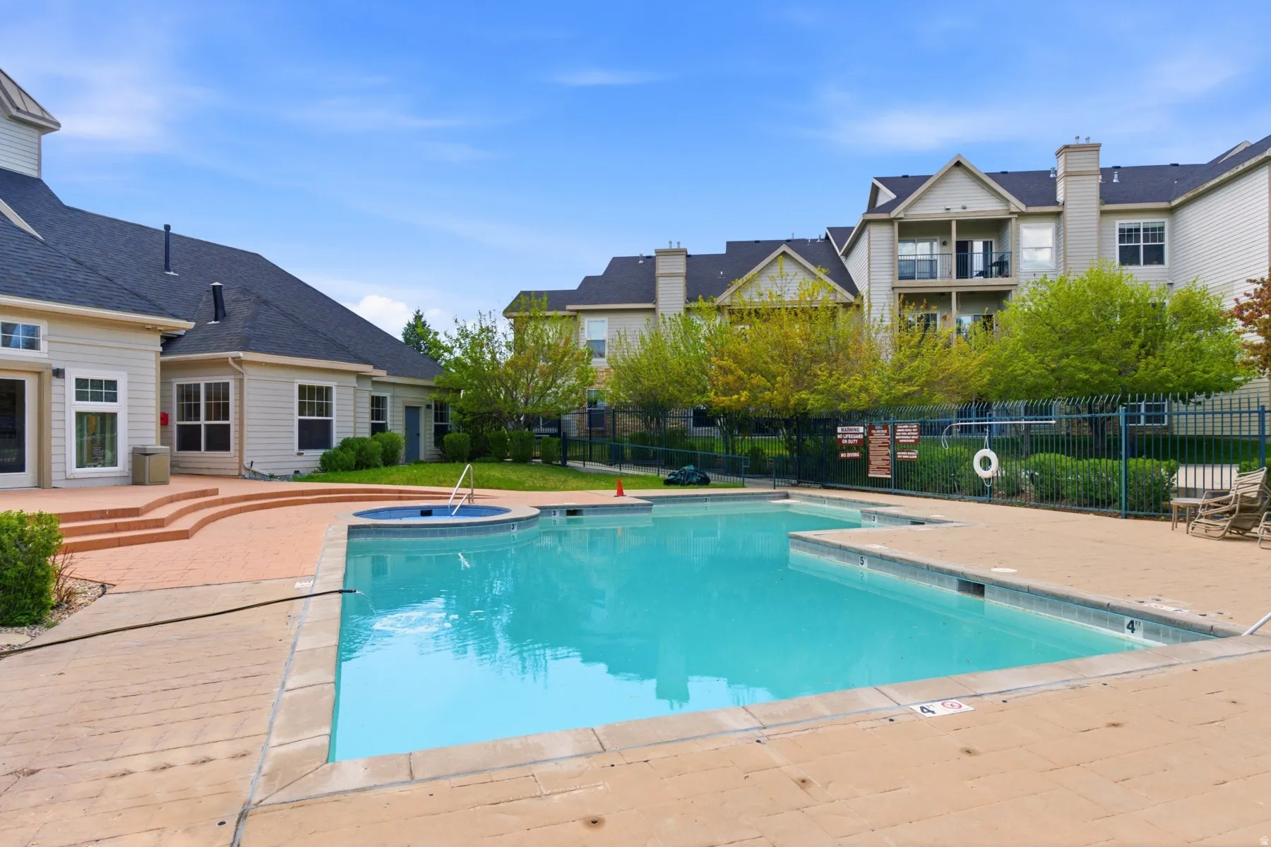 Resort-style outdoor pool with integrated spa, surrounded by a spacious brick paver deck