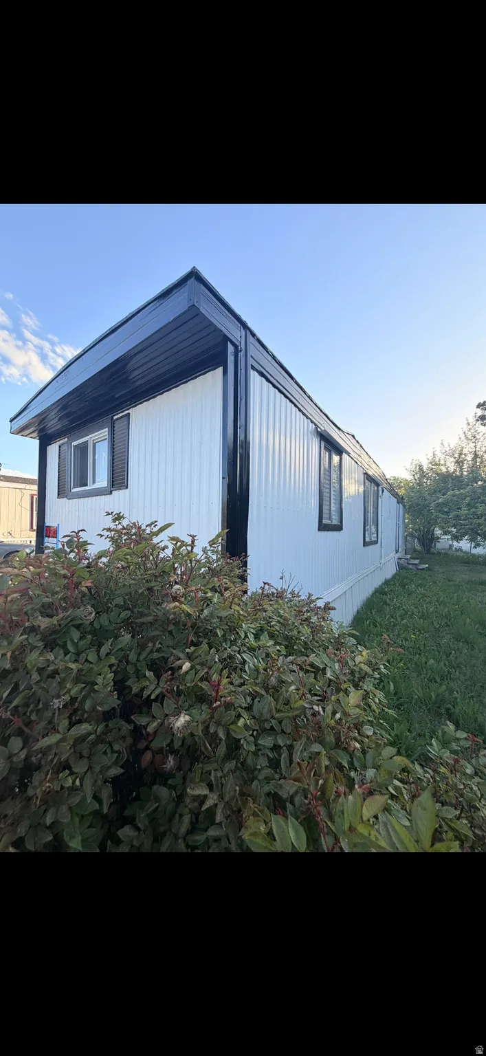 White siding exterior with black trim, multiple windows, and a dark-colored roof