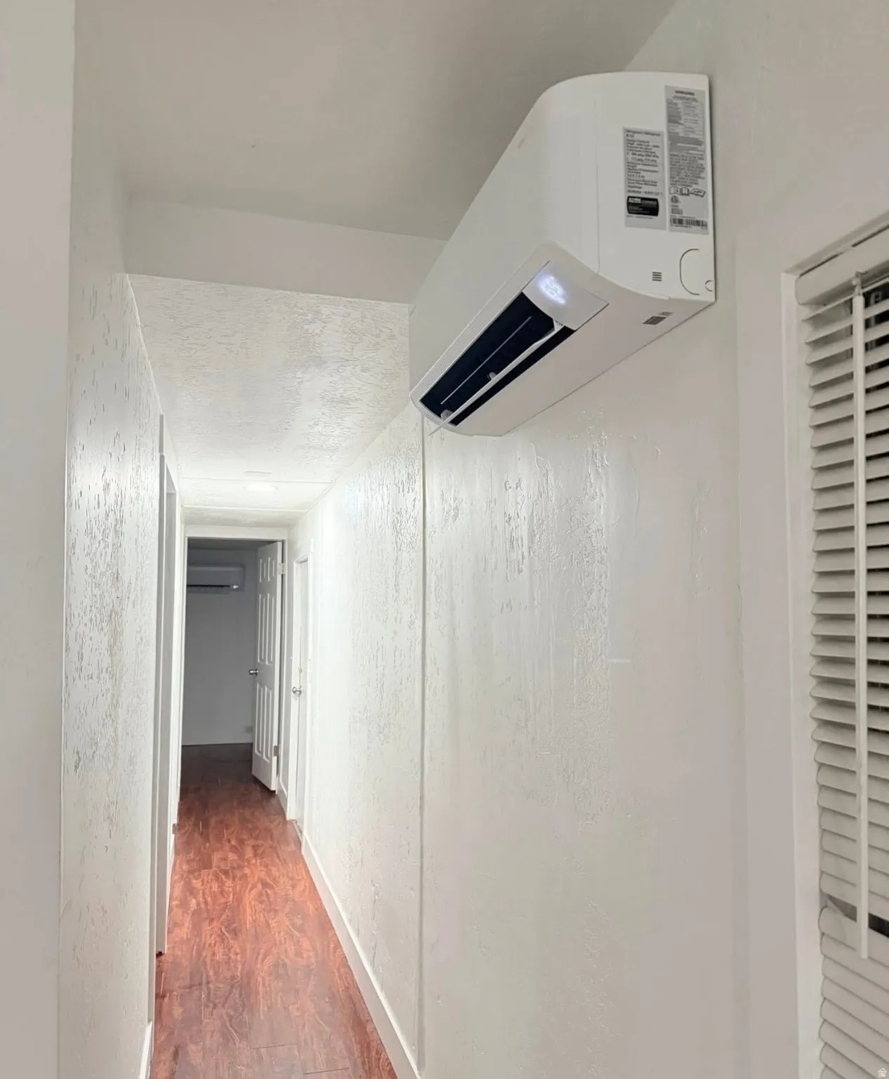 Ductless mini-split system unit mounted on a textured white wall, providing efficient climate control