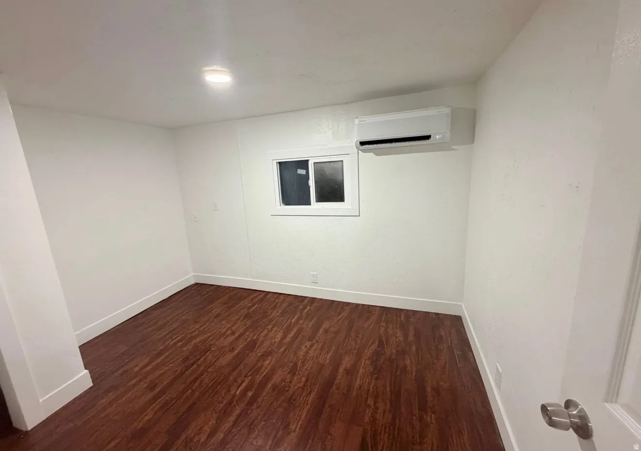 Bright room featuring rich wood-finish flooring and a white window frame
