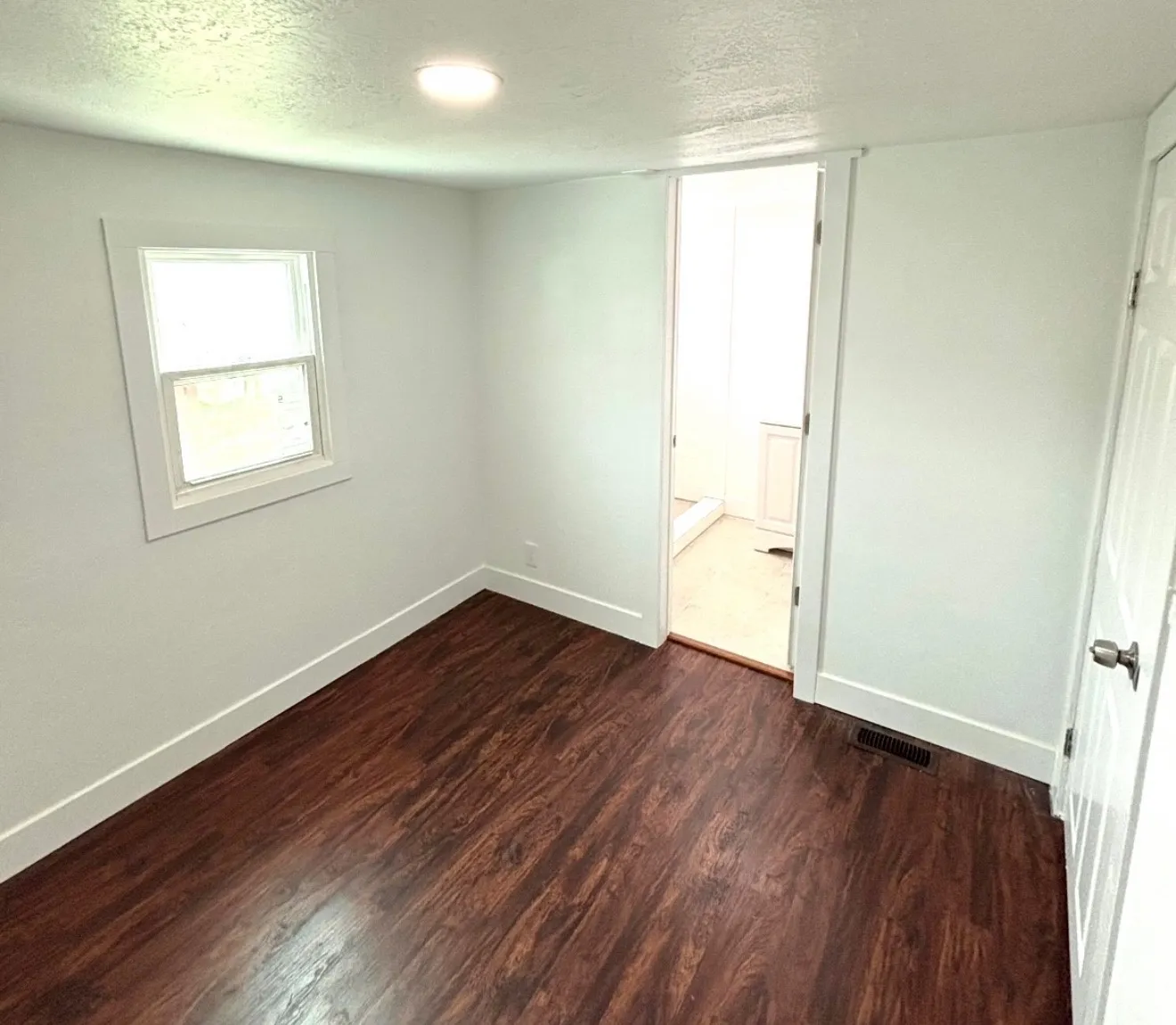 Interior room featuring wood-finish flooring, crisp white walls, and a recessed ceiling light